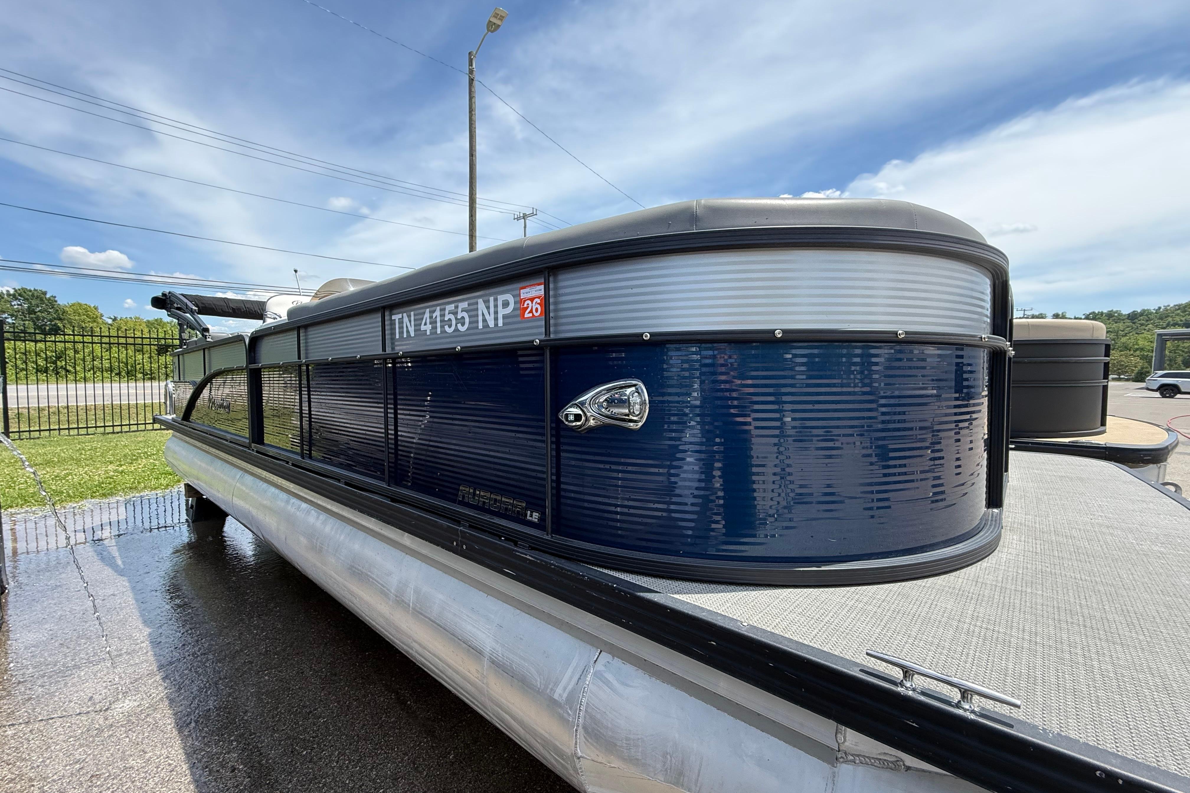 2022 Manitou Aurora LE pontoon boat with blue exterior, docked on a sunny day.