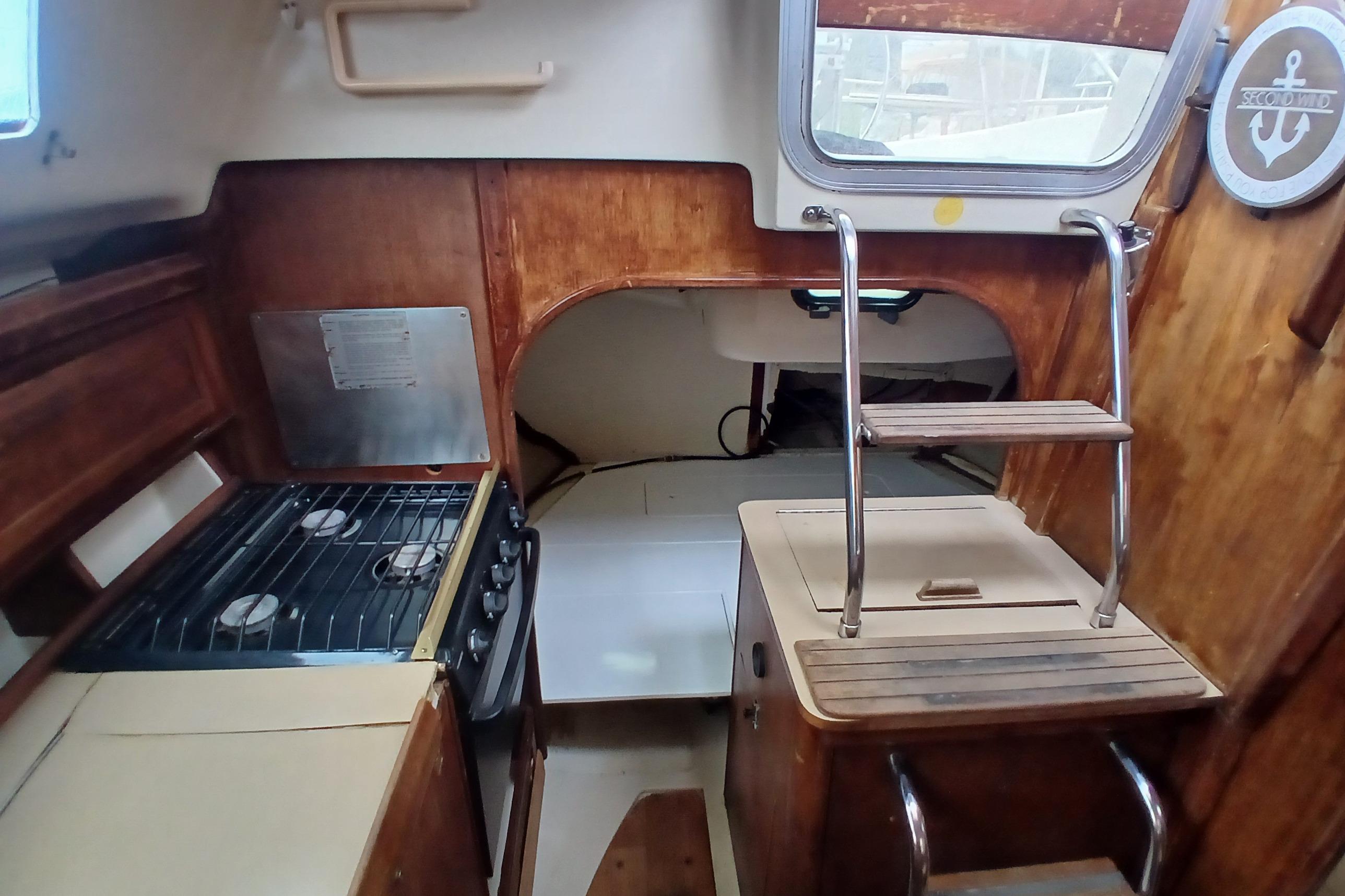 Interior of a 1994 Hunter 30 sailboat featuring a compact kitchen and wooden cabinetry.