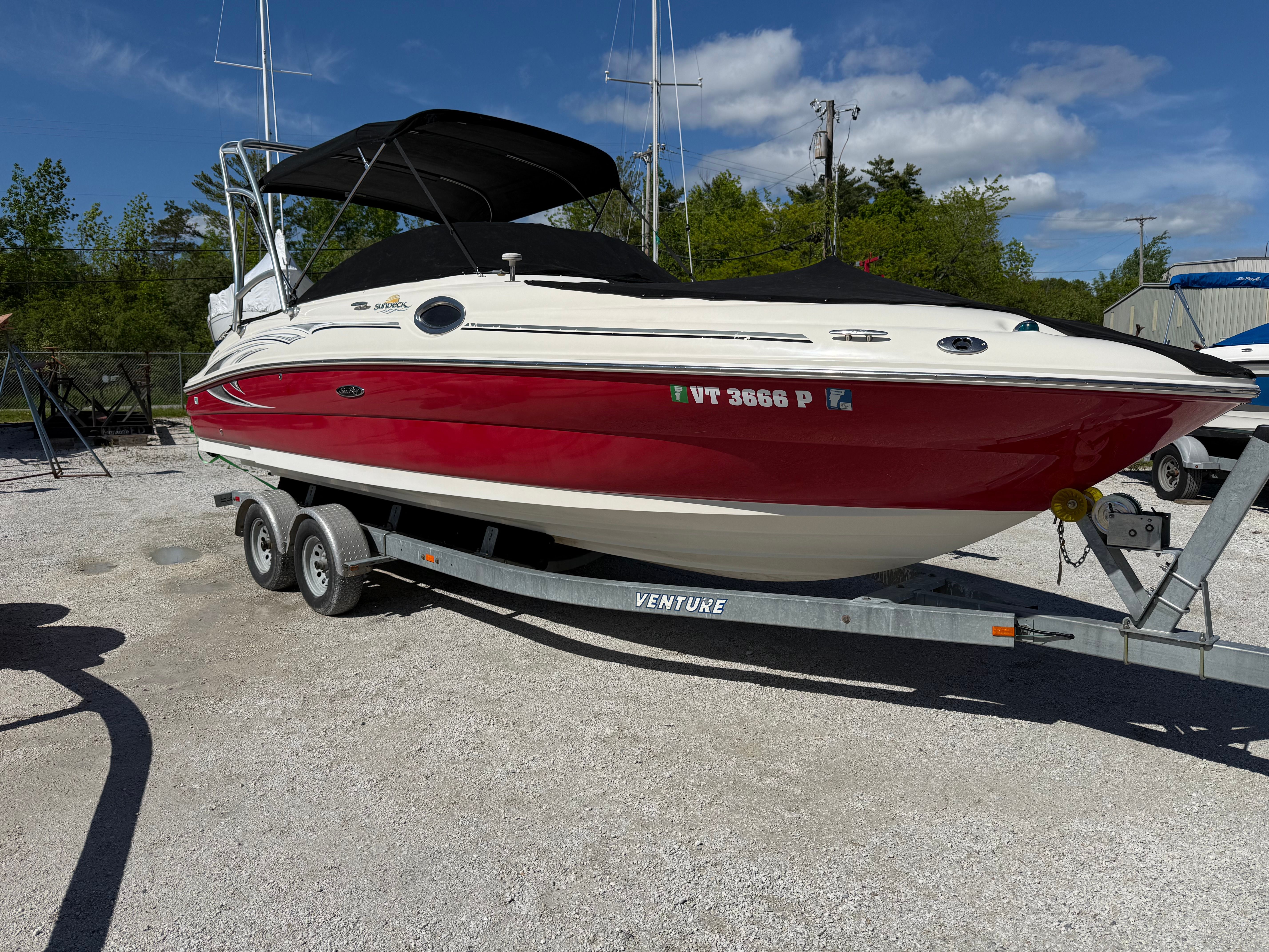 2005 Sea Ray 240 Sundeck on trailer, red and white design.