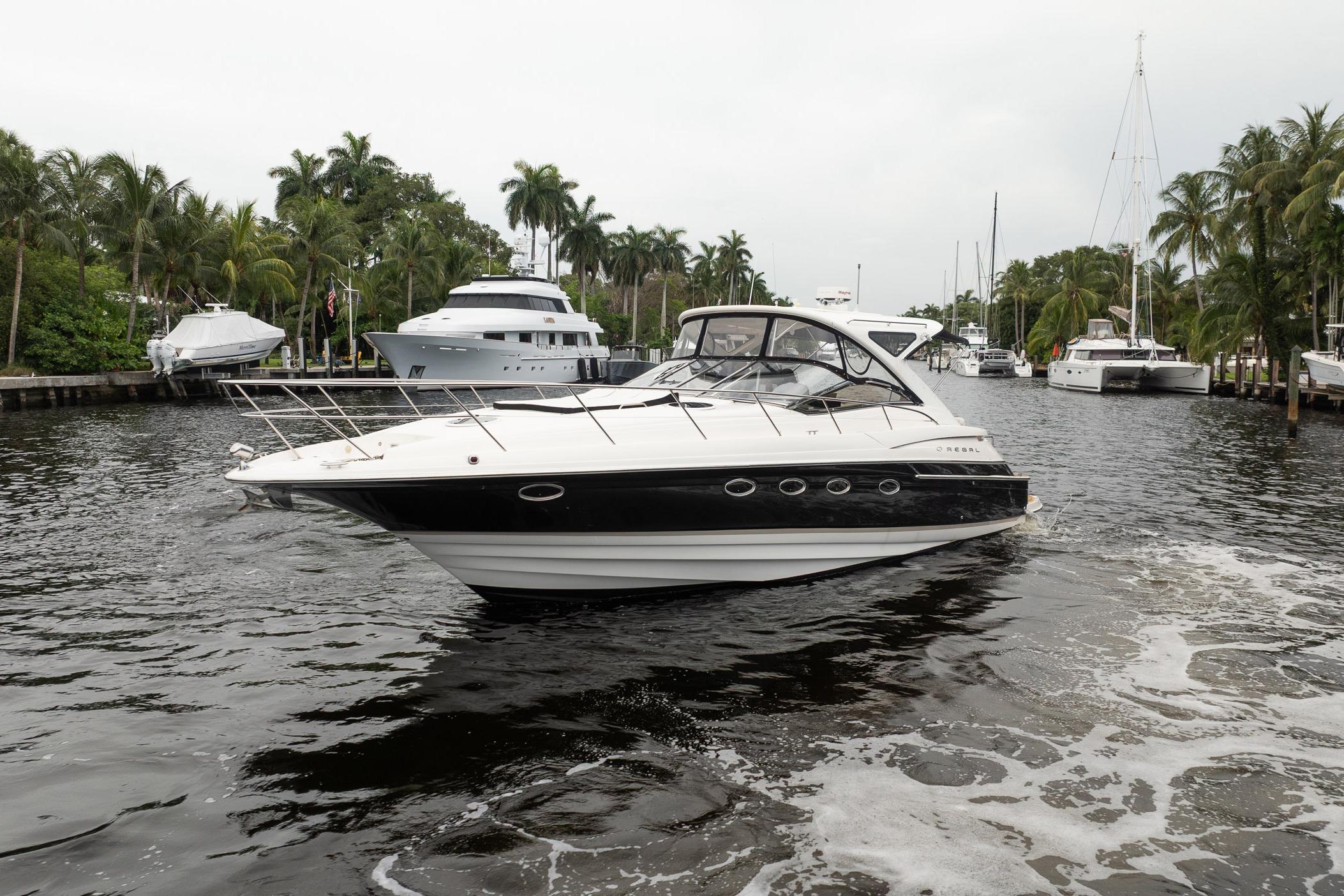 2008 Regal Commodore 4460 yacht cruising in a tropical marina with palm trees.