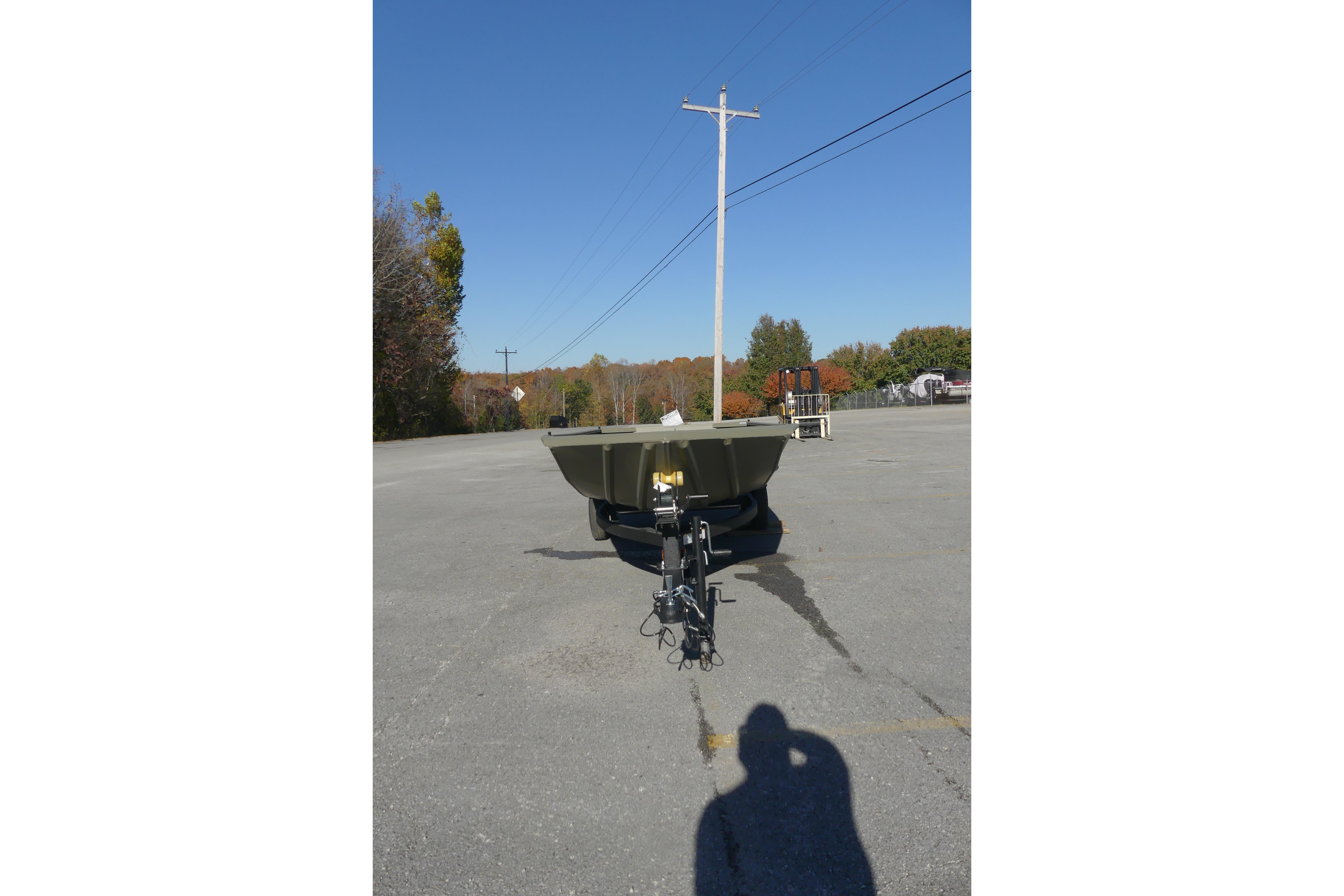 2026 Tracker Grizzly 1648 Utility boat in a parking lot under clear blue sky.