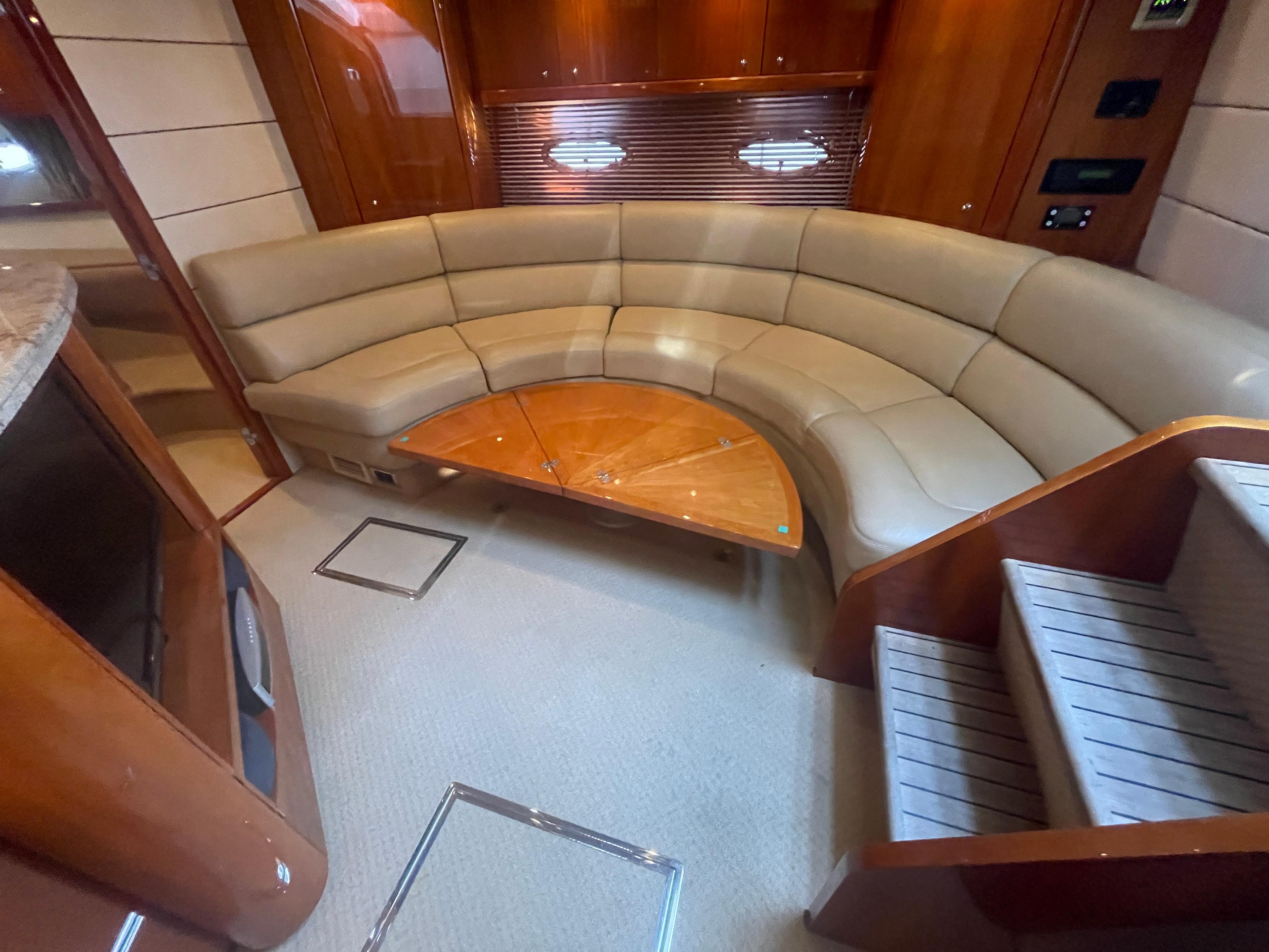 Luxurious interior of 2010 Sunseeker Portofino 47 yacht with curved seating and wooden accents.