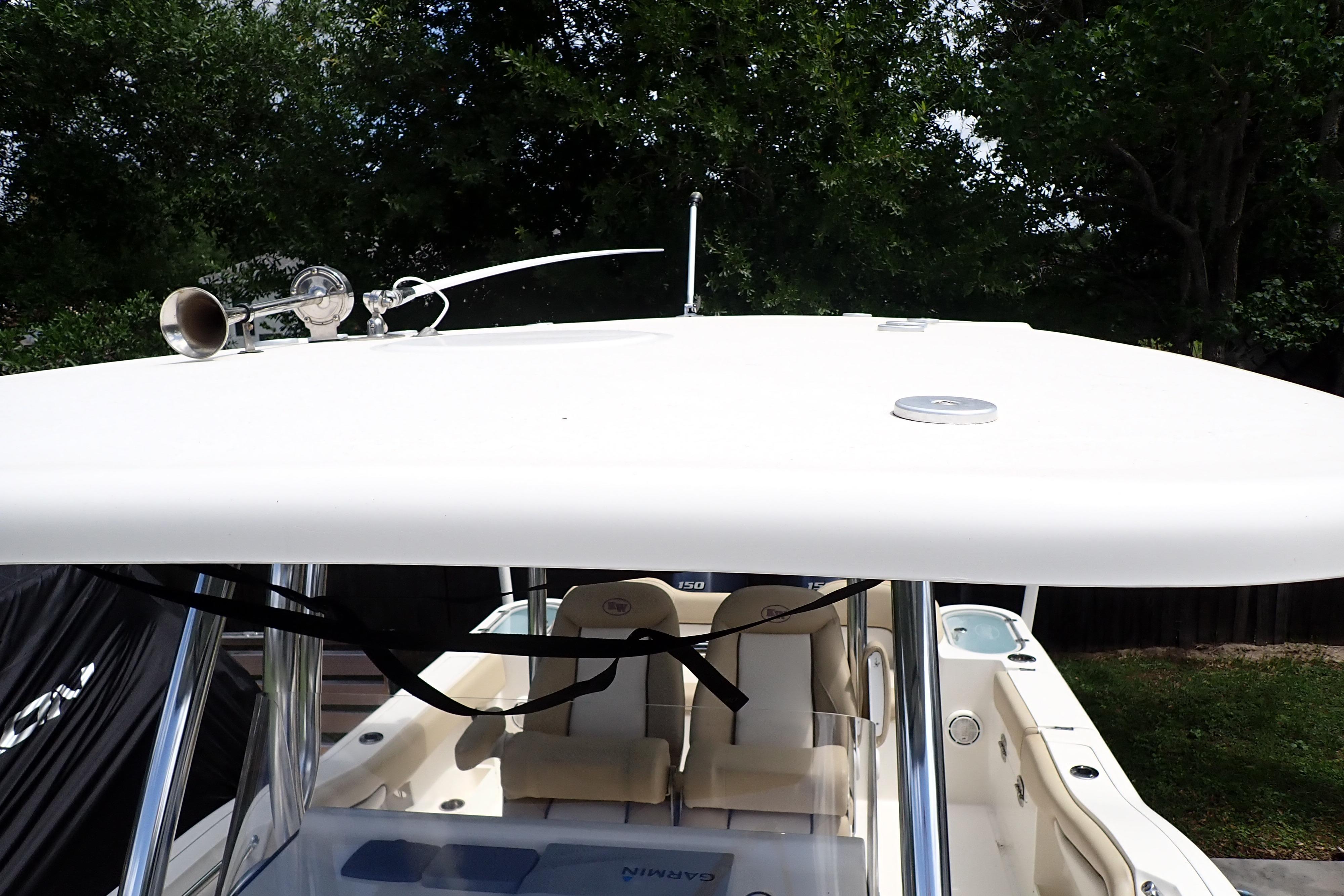 2019 Key West 263 FS boat with T-top and seating, surrounded by greenery.
