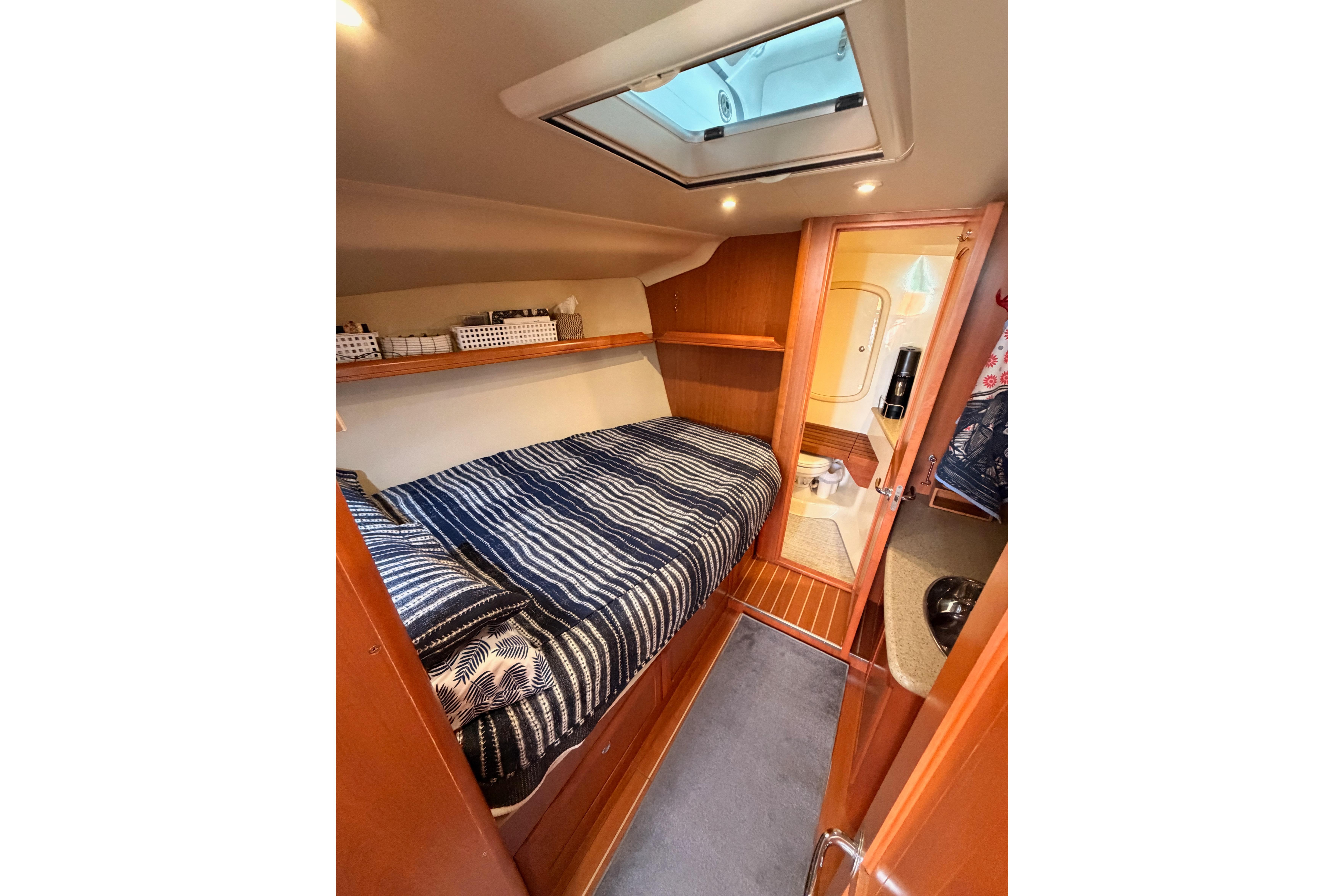 Cozy cabin interior of 2008 Hunter 45 Deck Salon yacht with striped bedding.
