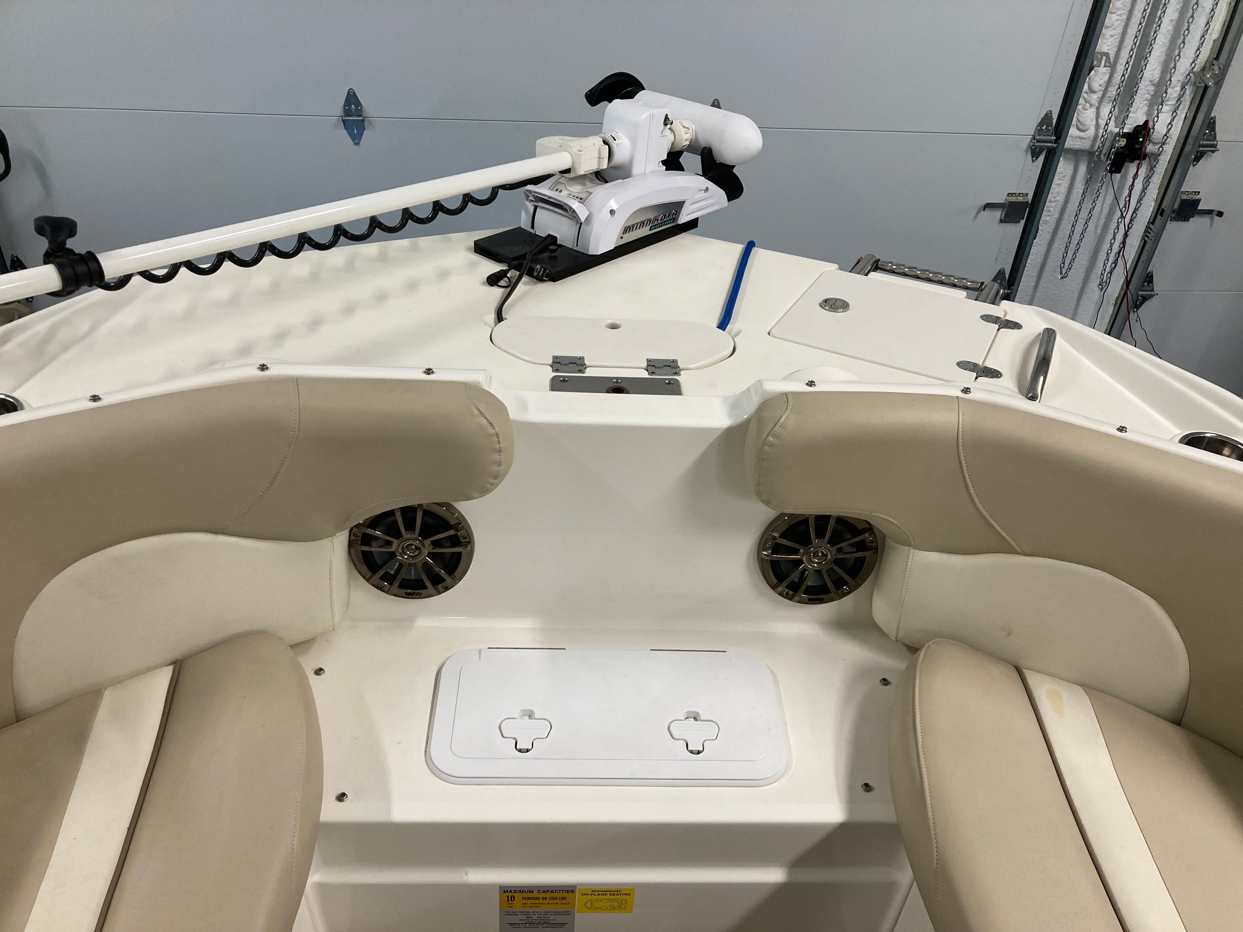 The image shows the bow of a boat with beige seats and a trolling motor.