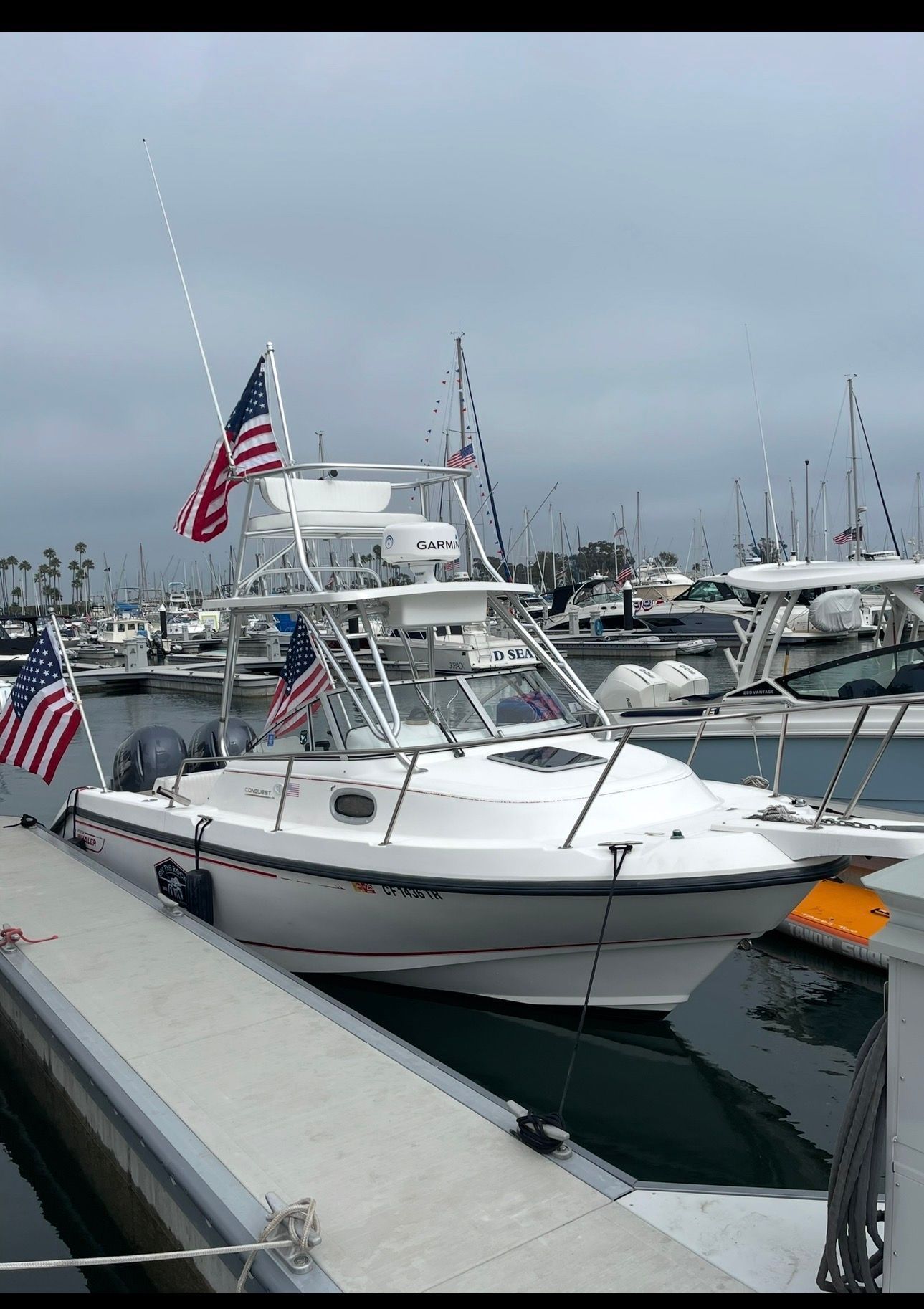 A 1997 Boston Whaler Conquest docked, featuring multiple American flags.