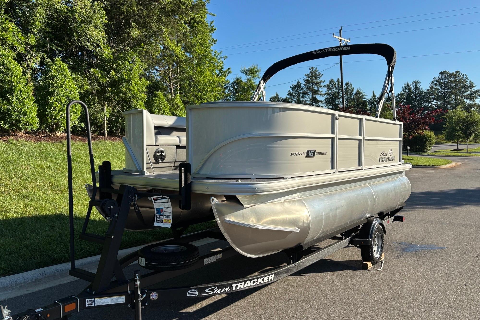 2026 Sun Tracker Party Barge 16 DLX pontoon boat on trailer, parked outdoors.