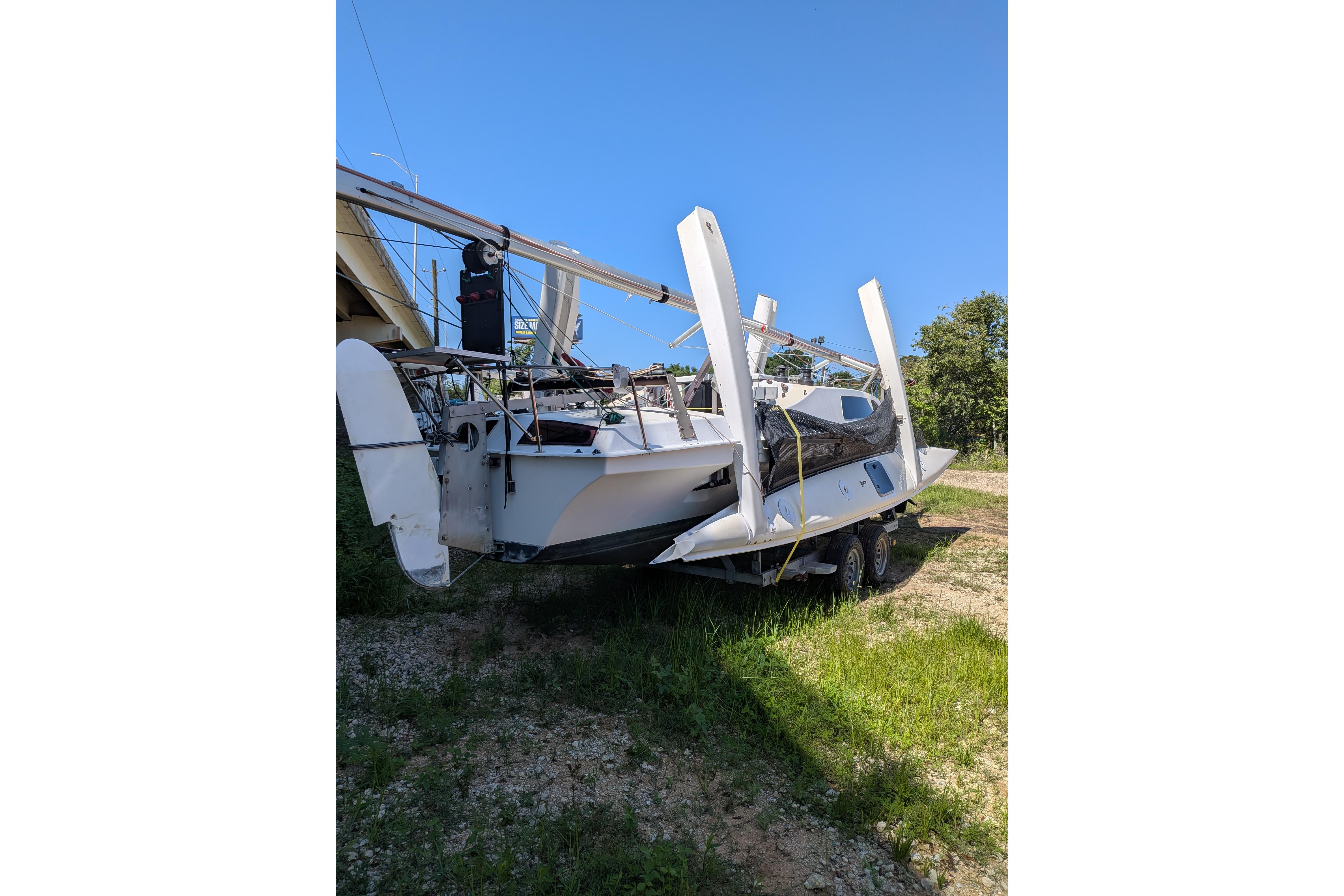 1991 Corsair F-27 sailboat on trailer, under clear blue sky.