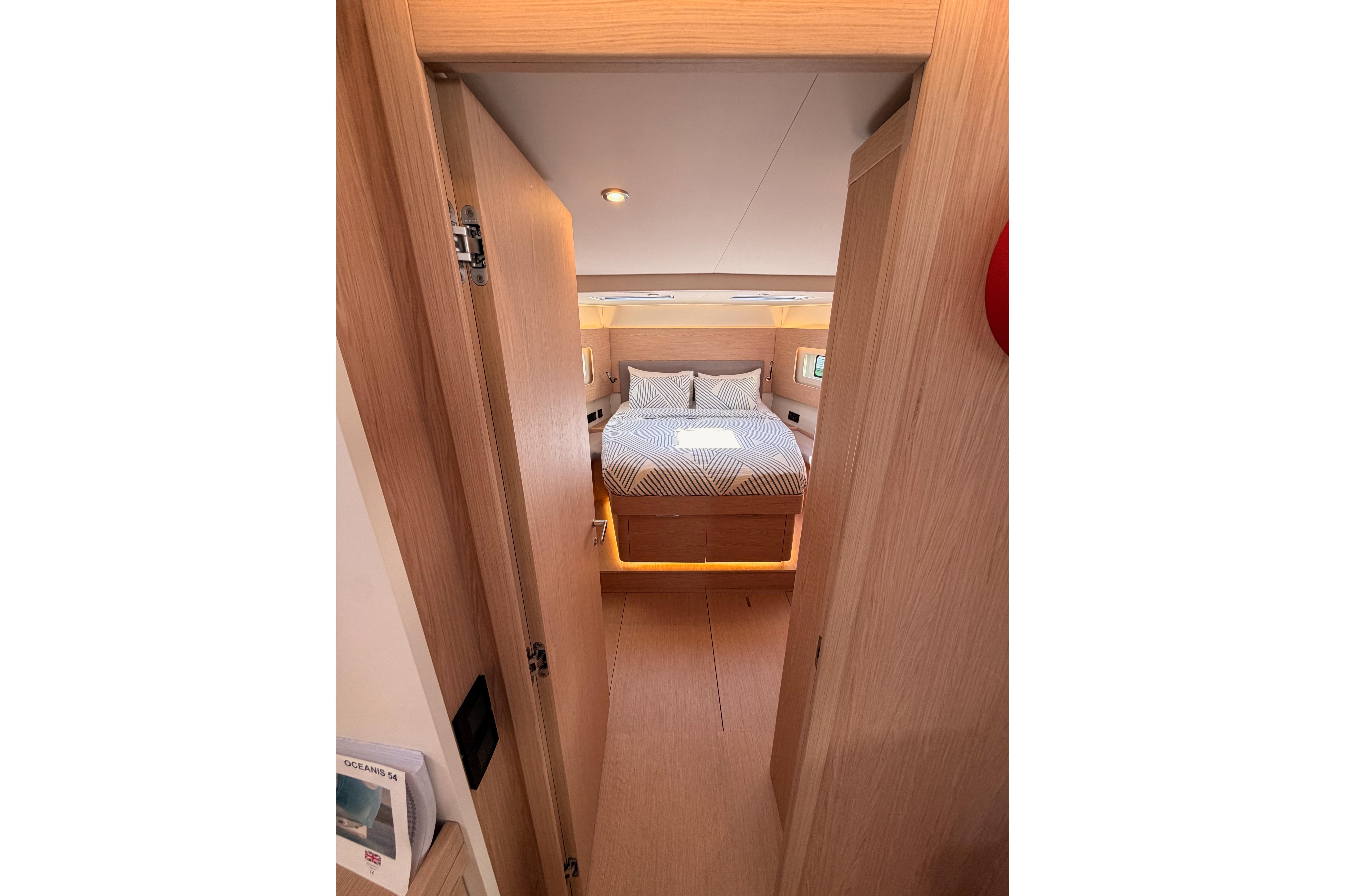 Luxurious cabin interior of 2022 Beneteau Oceanis Yacht 54, featuring a cozy bed and modern design.