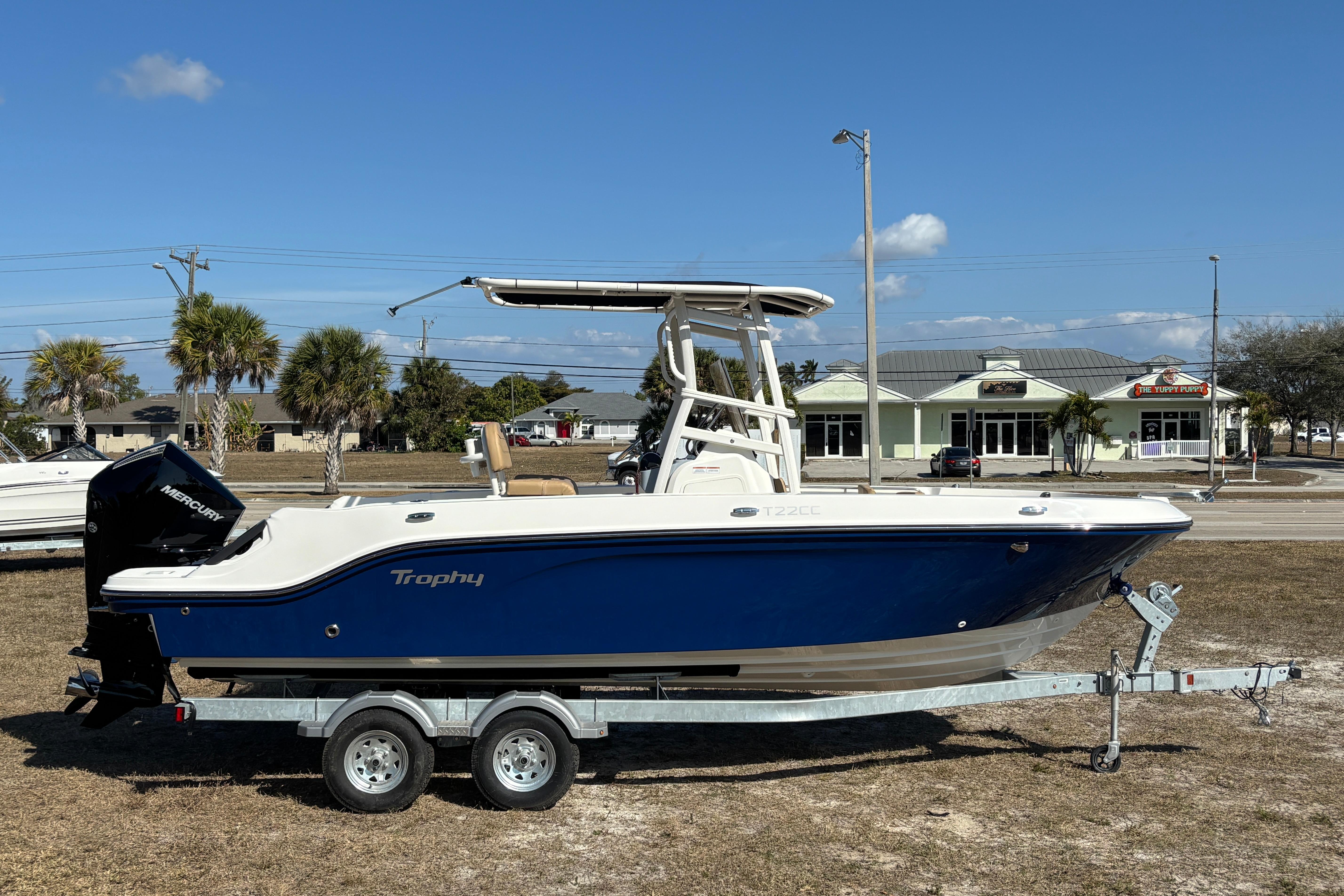2026 Bayliner Trophy T22CC boat on trailer, blue and white design, parked outdoors.