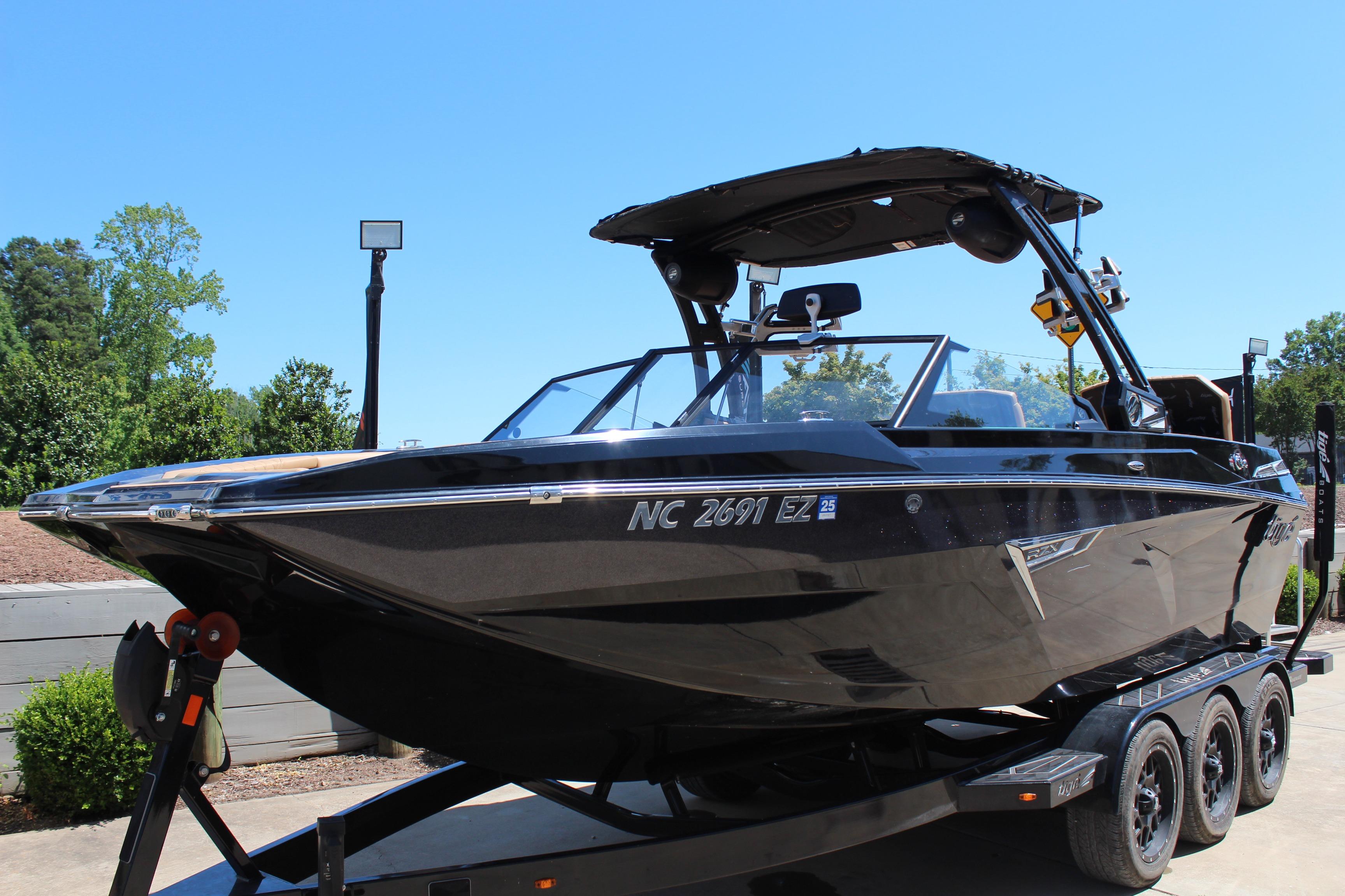2022 Tigé 22RZX boat on trailer, sleek black design, parked outdoors.