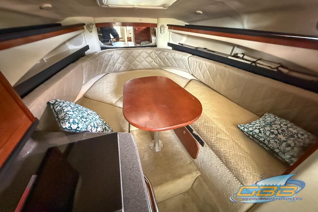 Interior of 2006 Sea Ray Sundancer 260 with cozy seating and wooden table.