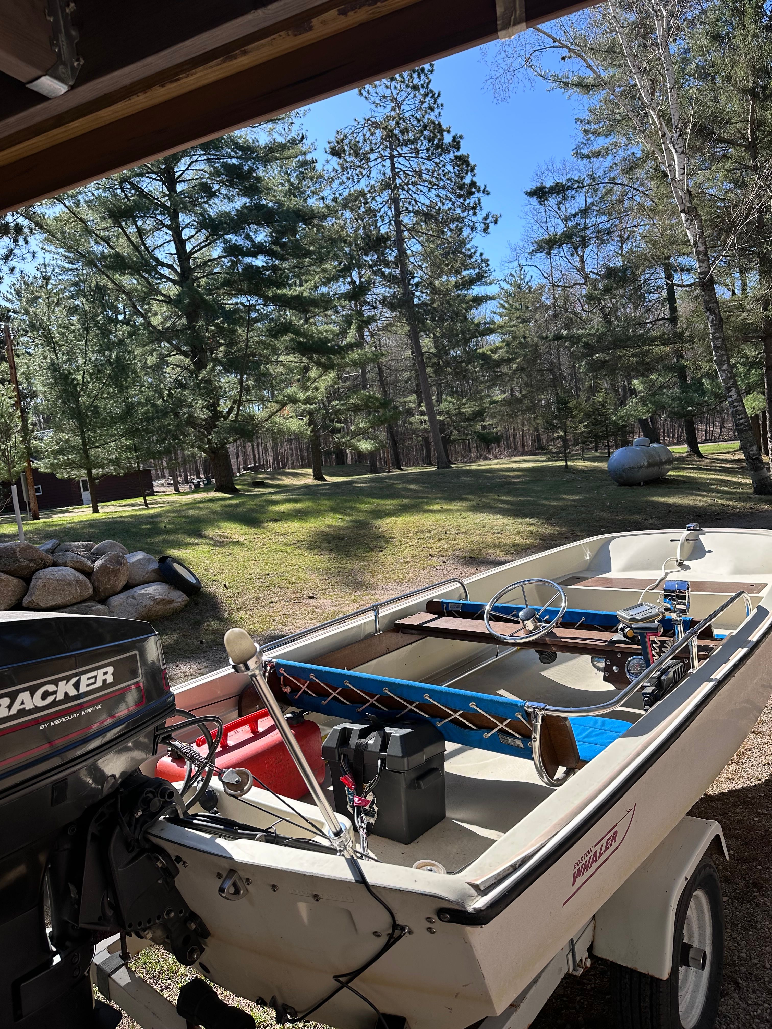 1973 Boston Whaler Sourpuss boat parked in a wooded area.