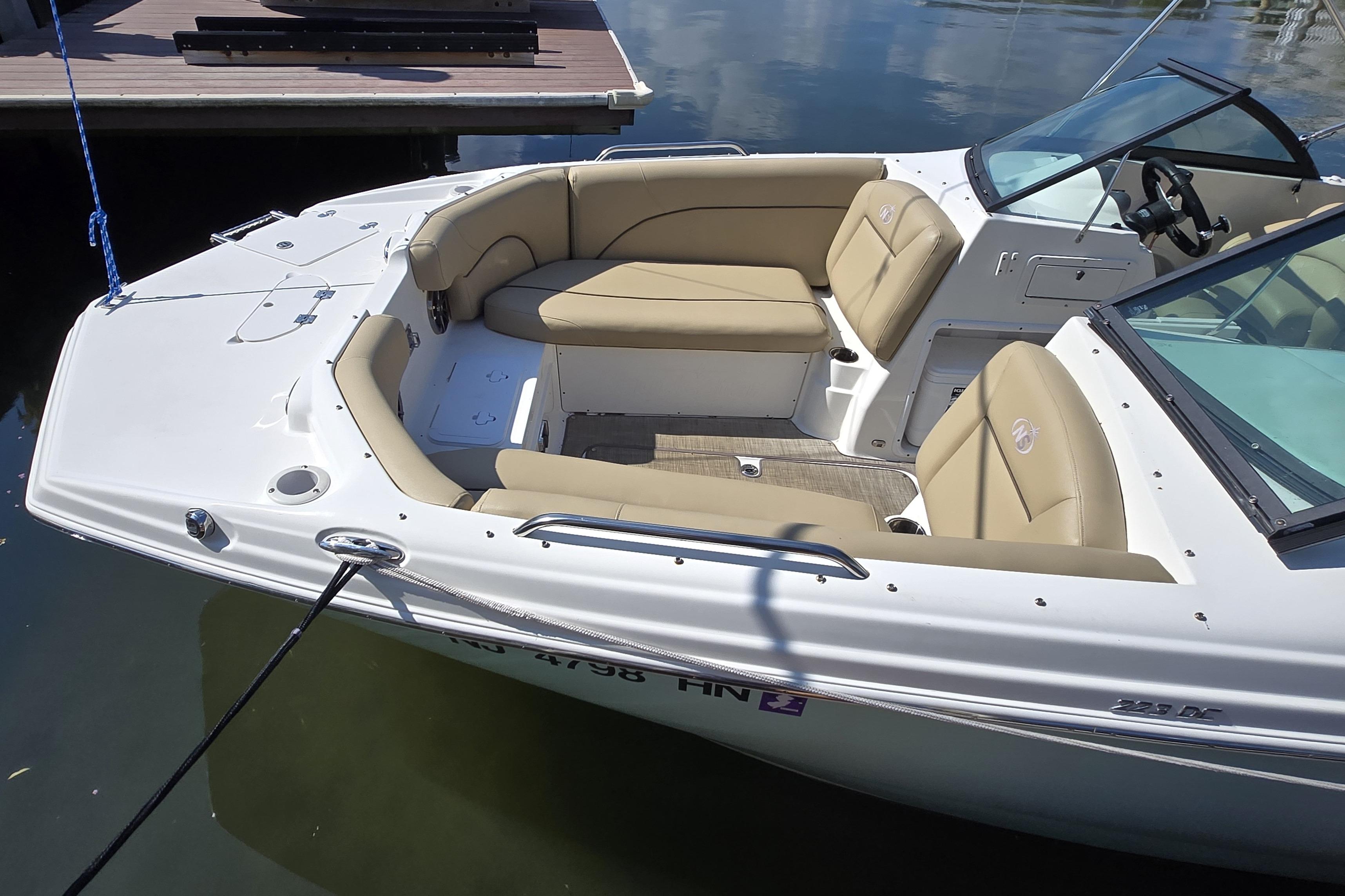 2020 NauticStar 223 DC boat with beige seating, docked on calm water.