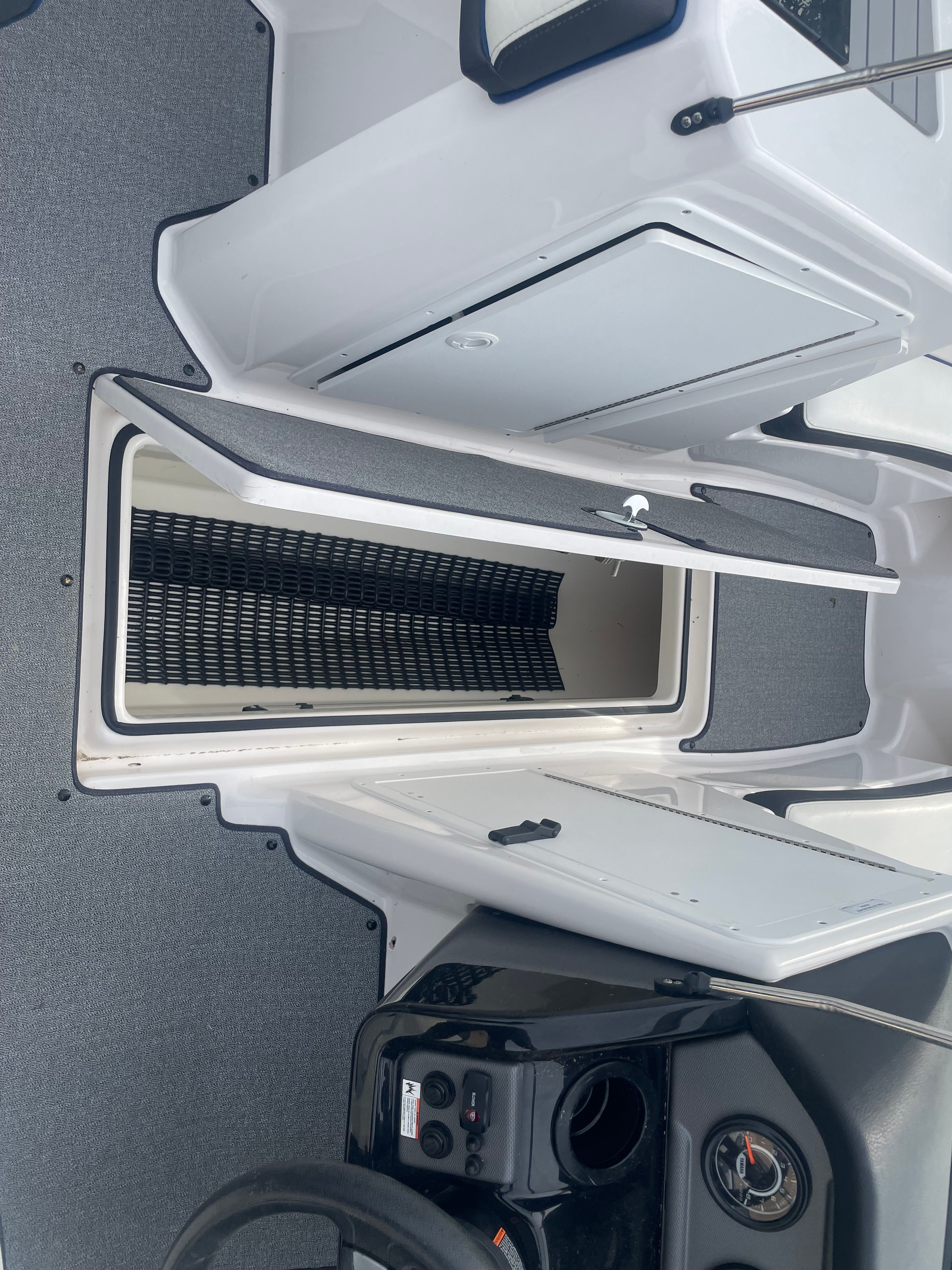 The image shows the interior of a 2019 Yamaha SX210 boat with storage and a helm console.