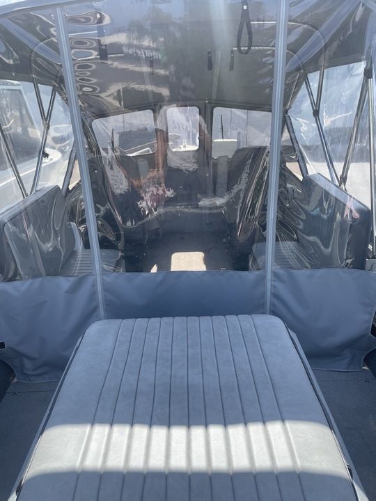 Interior view of a boat with gray seating and transparent covers.