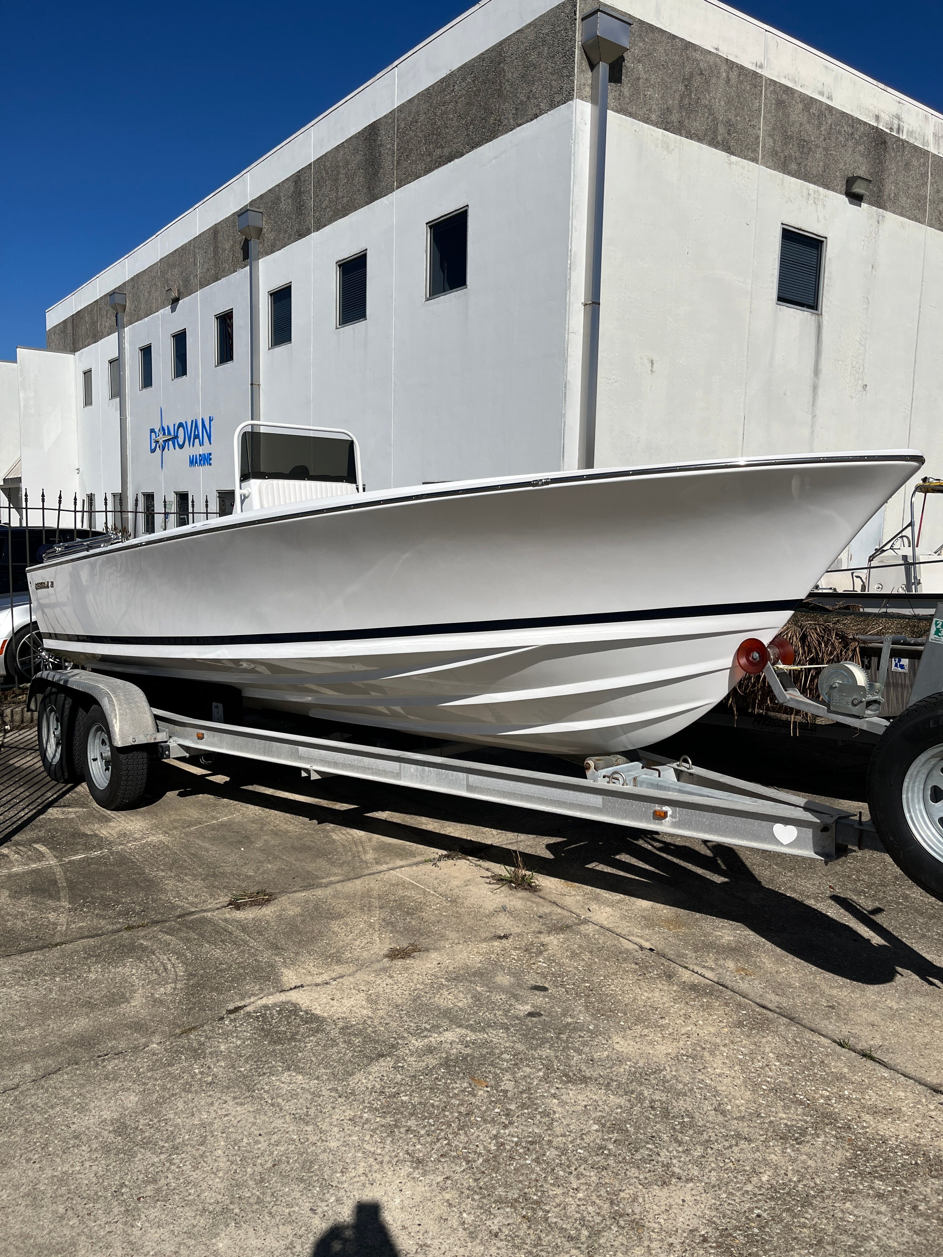 1970 Bertram Sportsman boat on trailer outside building.
