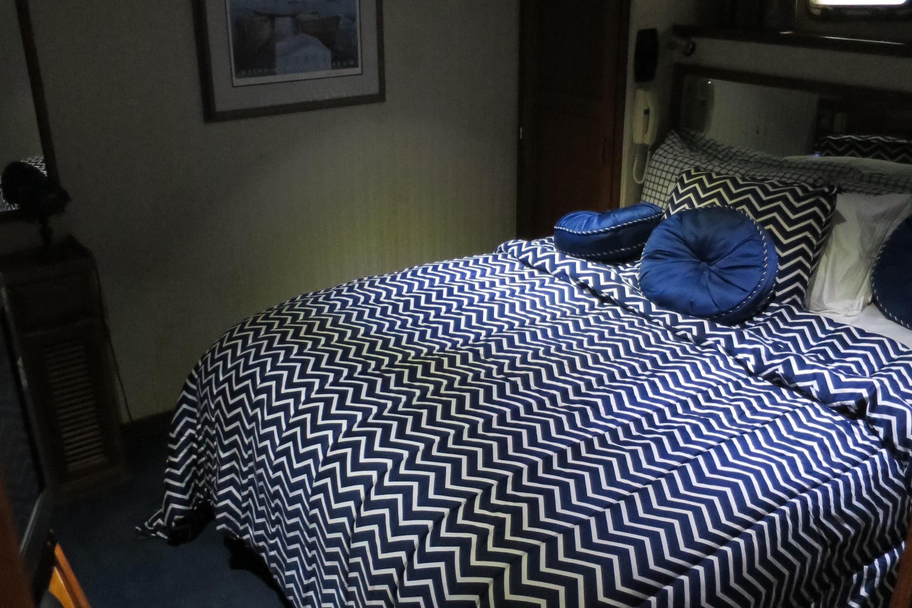 Bedroom interior of 1988 DeFever 53POC yacht with chevron-patterned bedding.