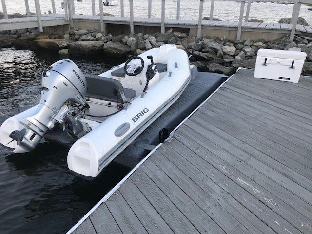 A white 2018 Brig Falcon 330 inflatable boat is docked at a wooden pier.