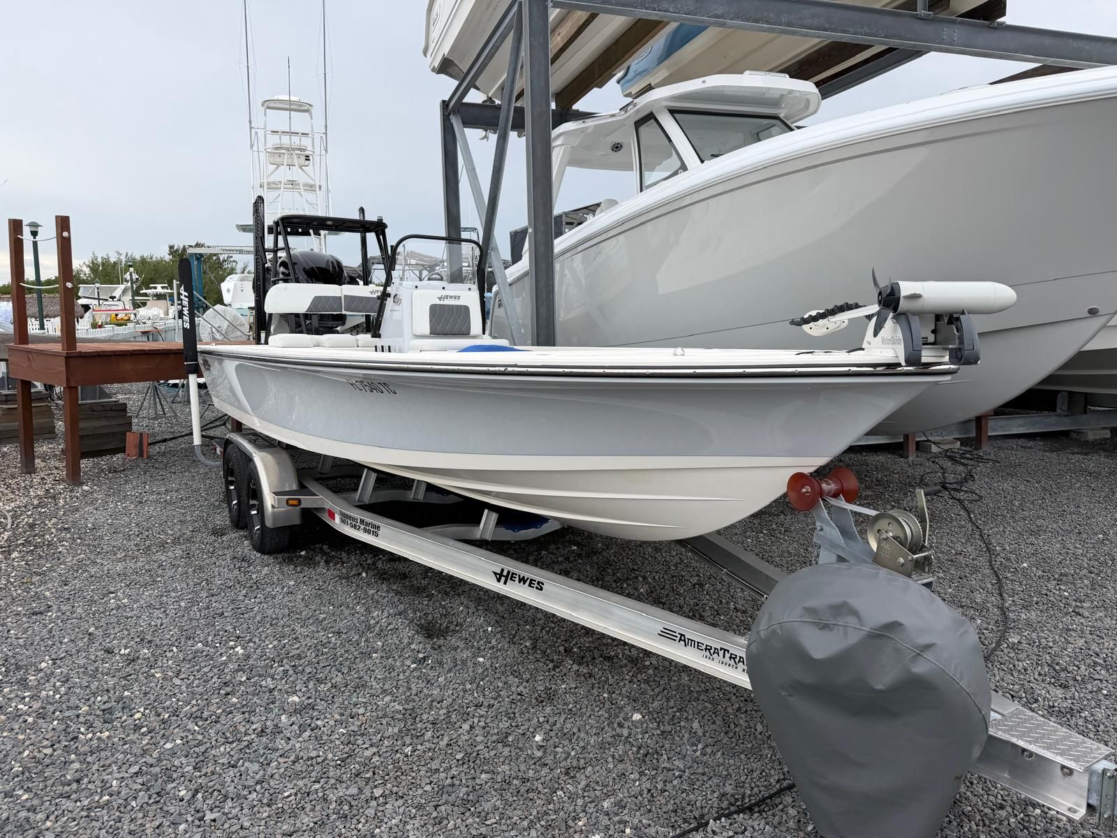A 2022 Hewes Redfisher 21 on a trailer, parked on gravel next to other boats.