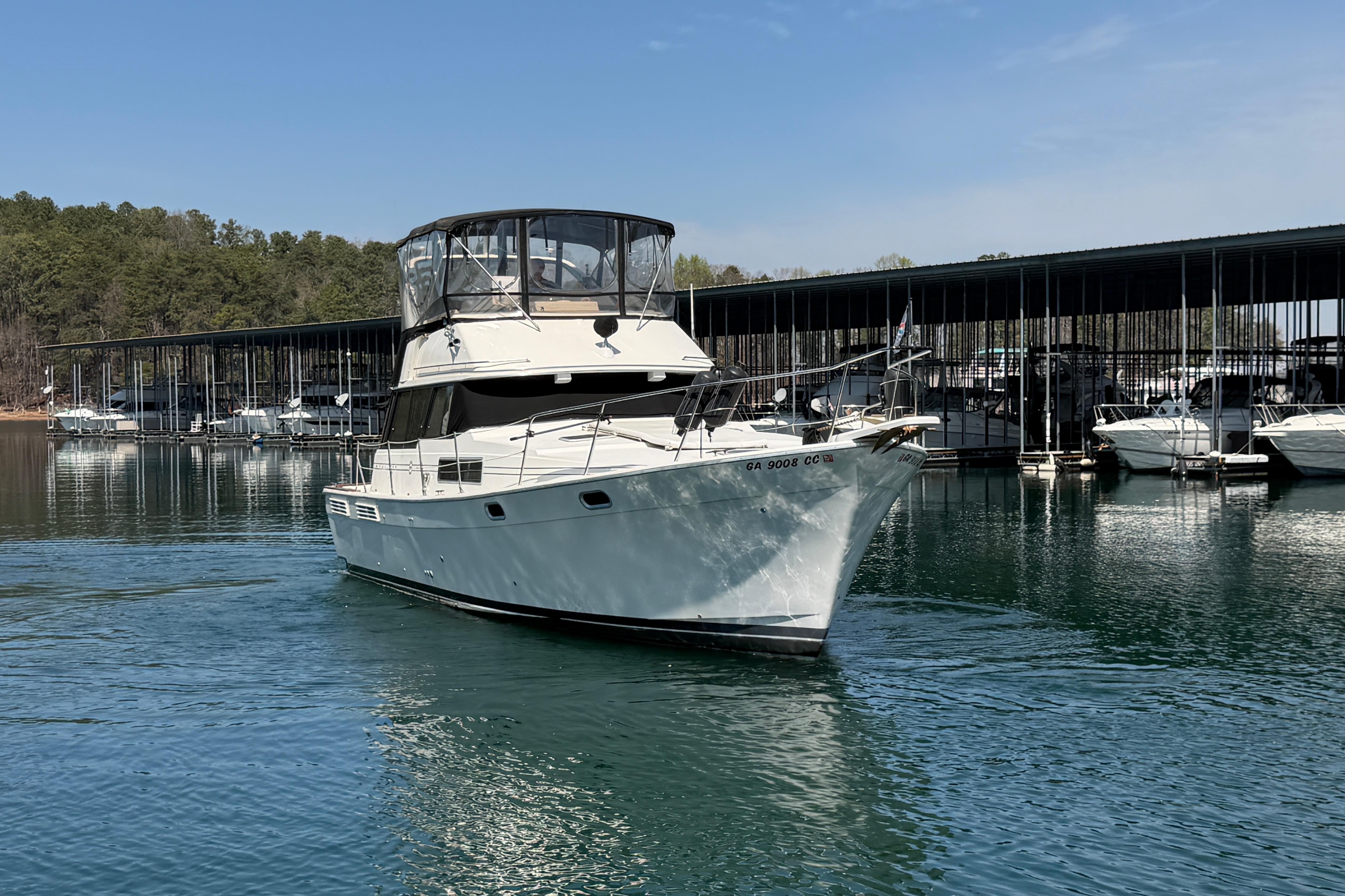 1994 Bayliner 3888 MY Sedan yacht docked on a serene lake with marina backdrop.