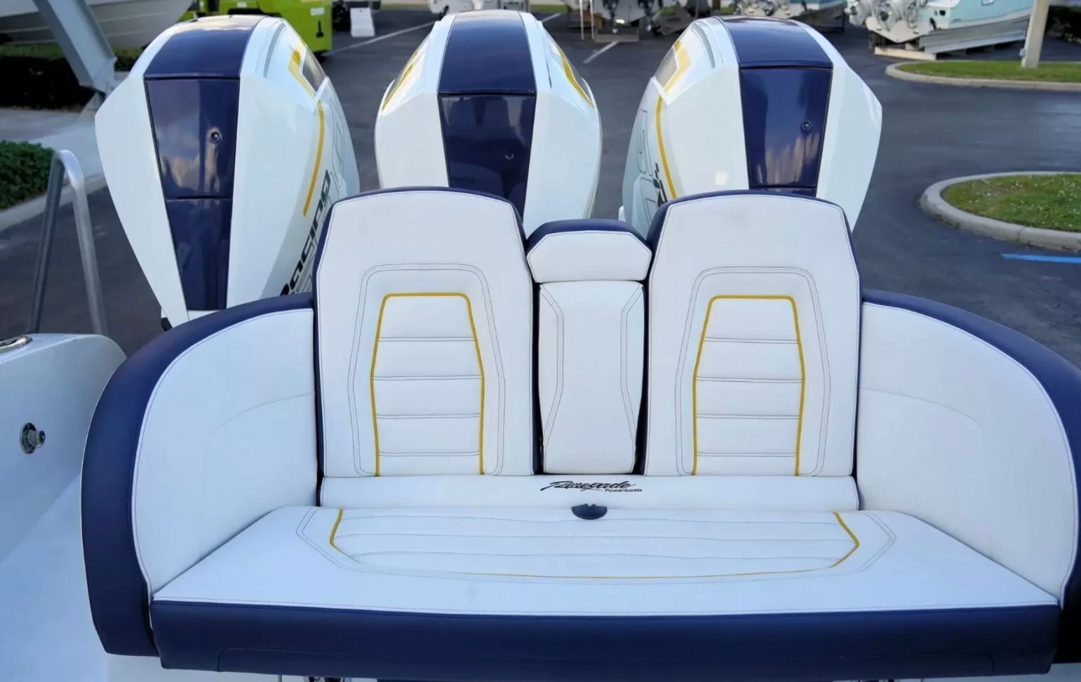 The image shows the rear of a boat with three engines and a cushioned bench seat.