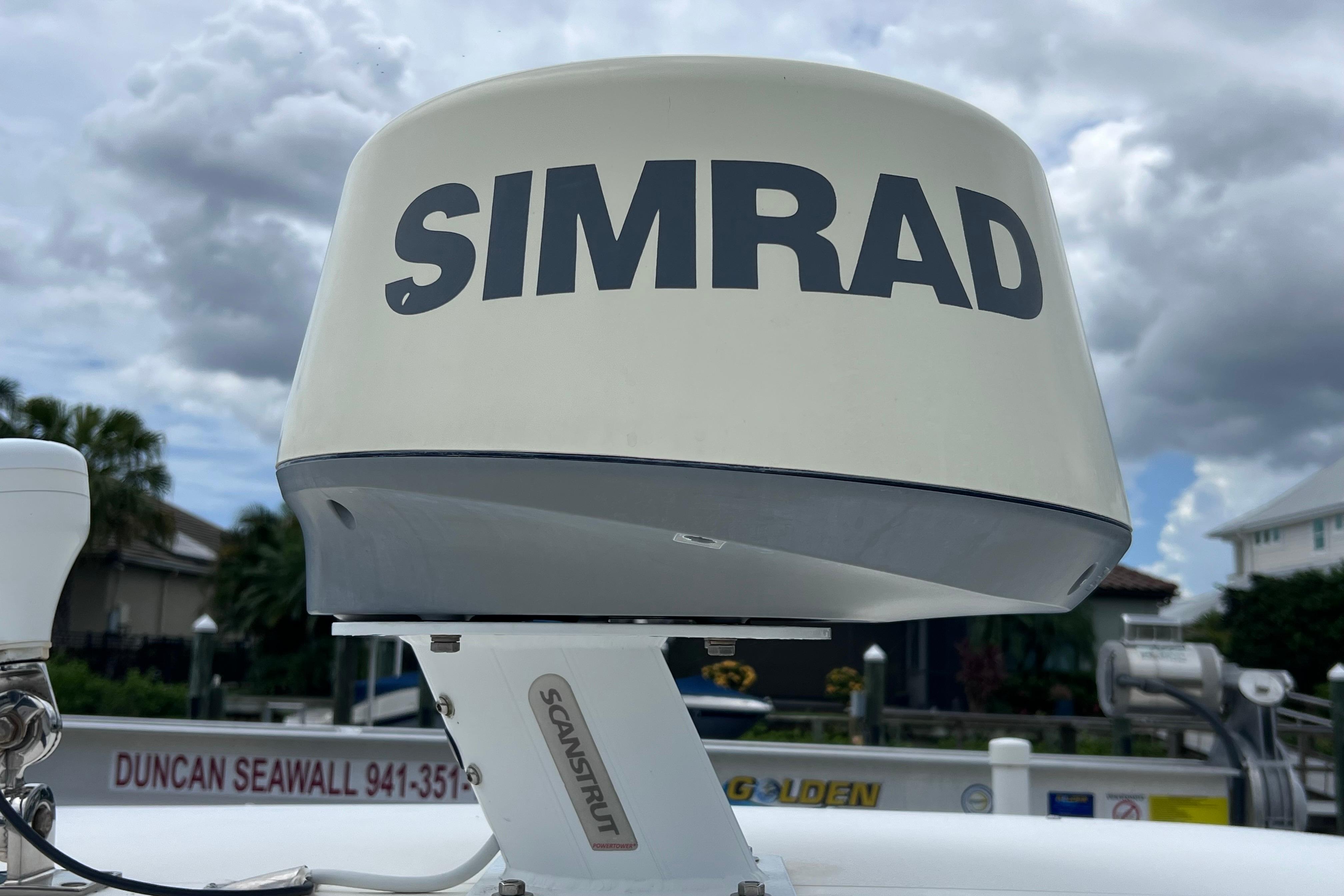 Simrad radar on 2005 Pursuit 3070 Offshore boat, cloudy sky background.