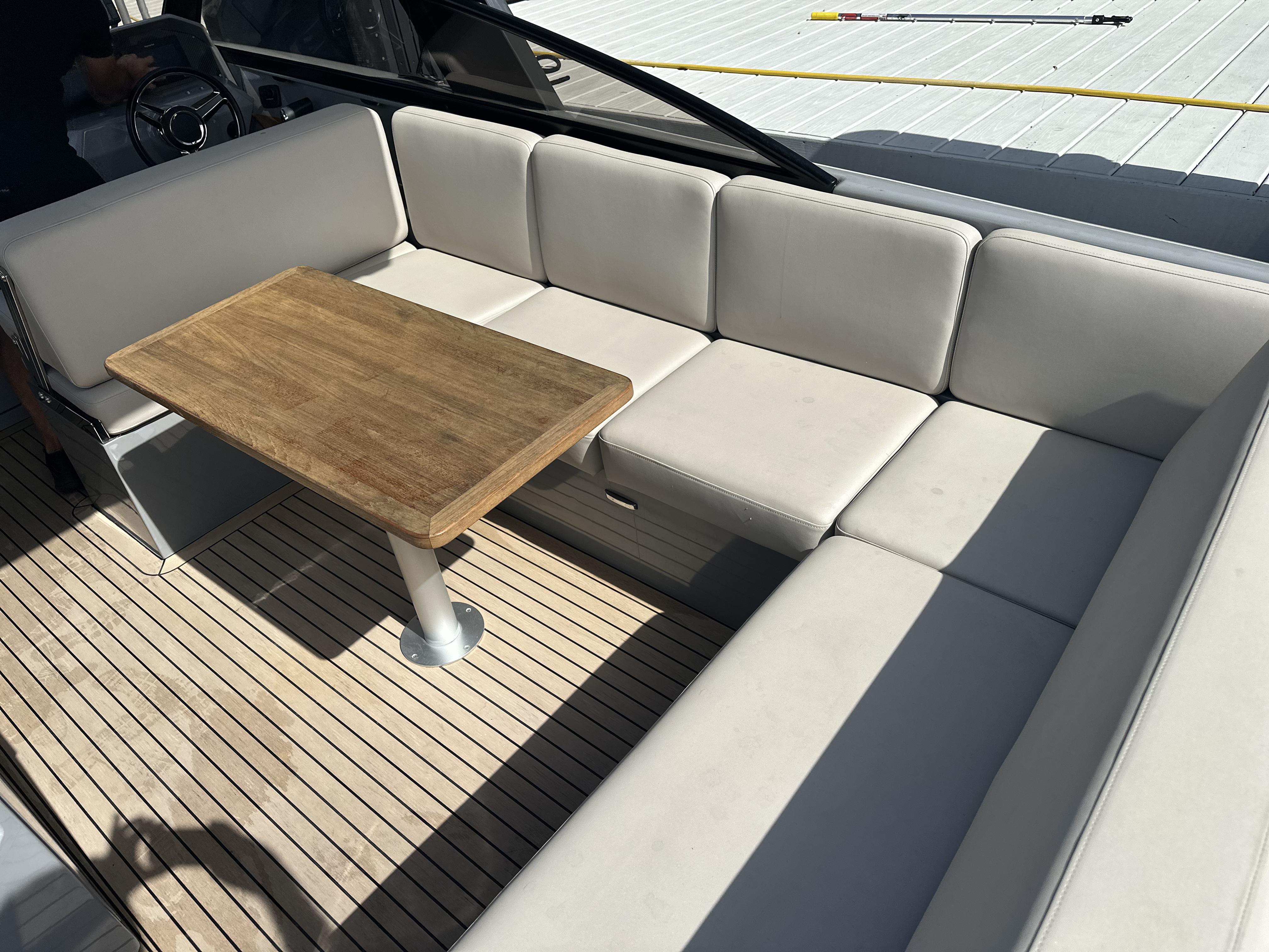 Luxurious seating area on 2021 Rand Leisure boat with wooden table and cushioned seats.
