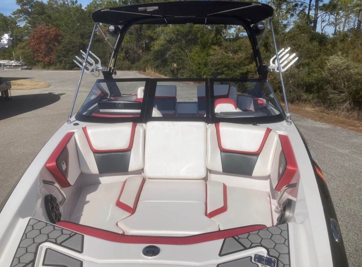 A 2017 Scarab 215 boat with red and white seating, parked on a lot.