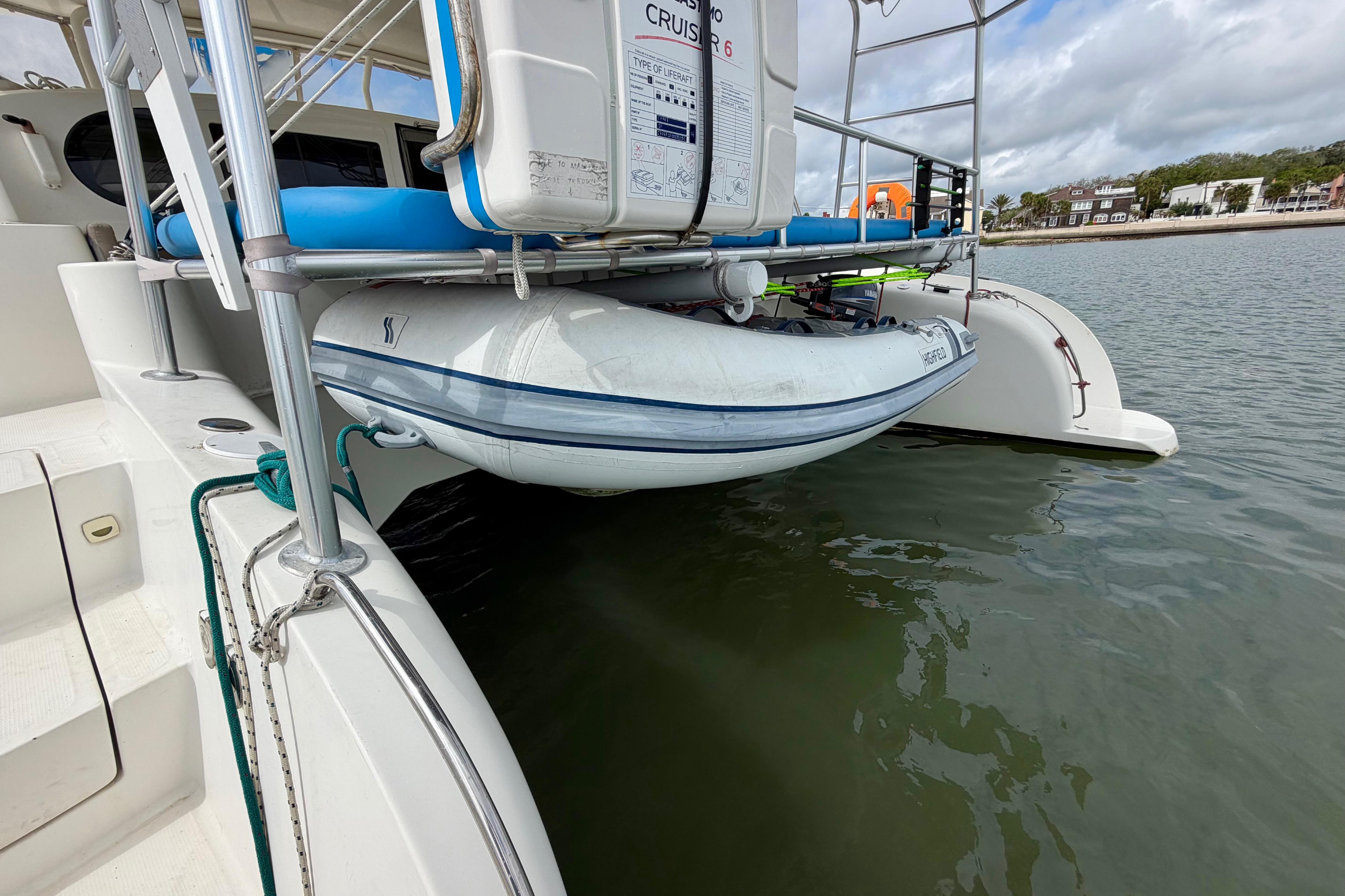 Inflatable boat secured on Dolphin 460 yacht, 2007 model, near a calm shoreline.