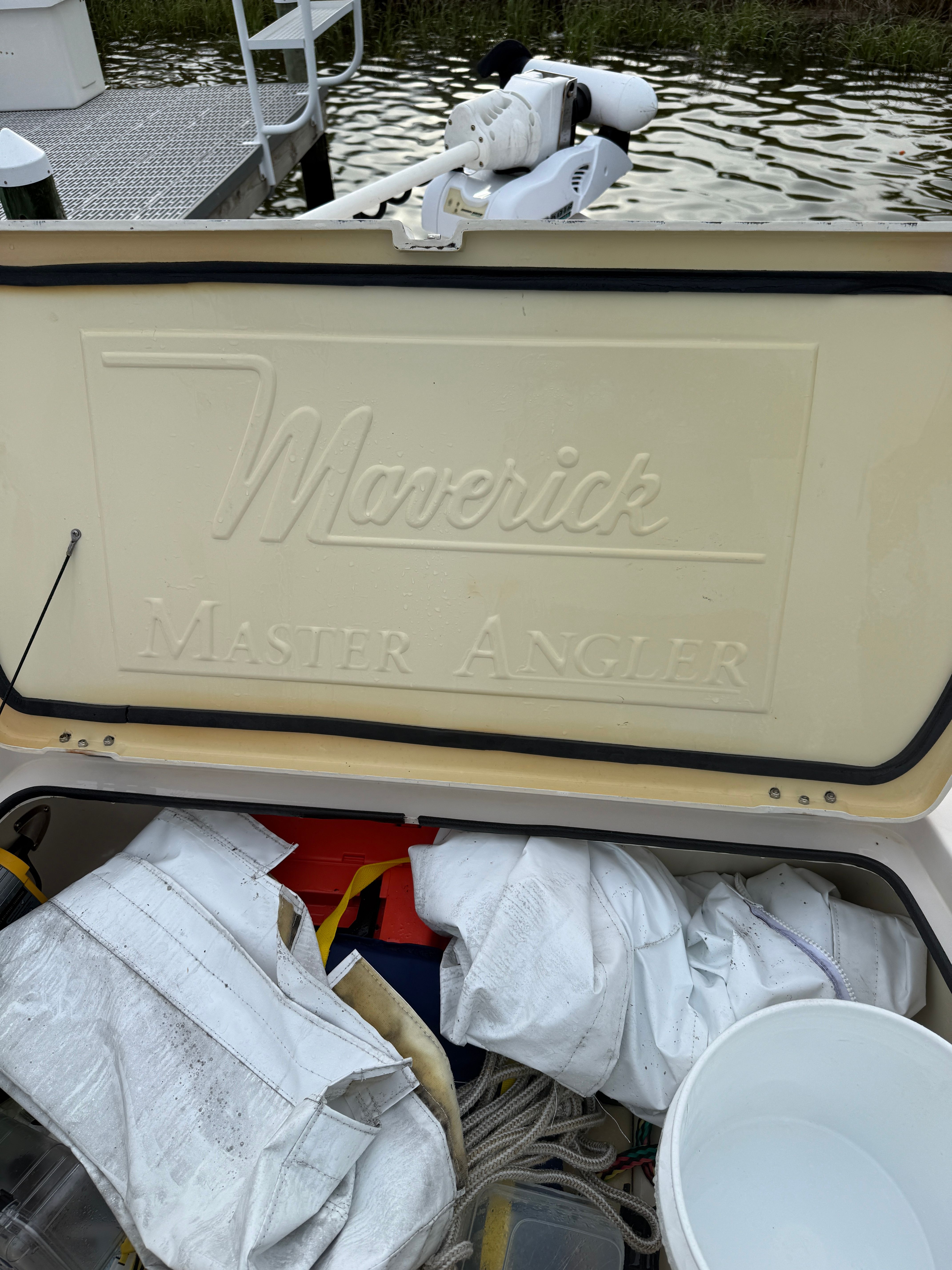 A Maverick Master Angler boat with storage full of gear by the water.