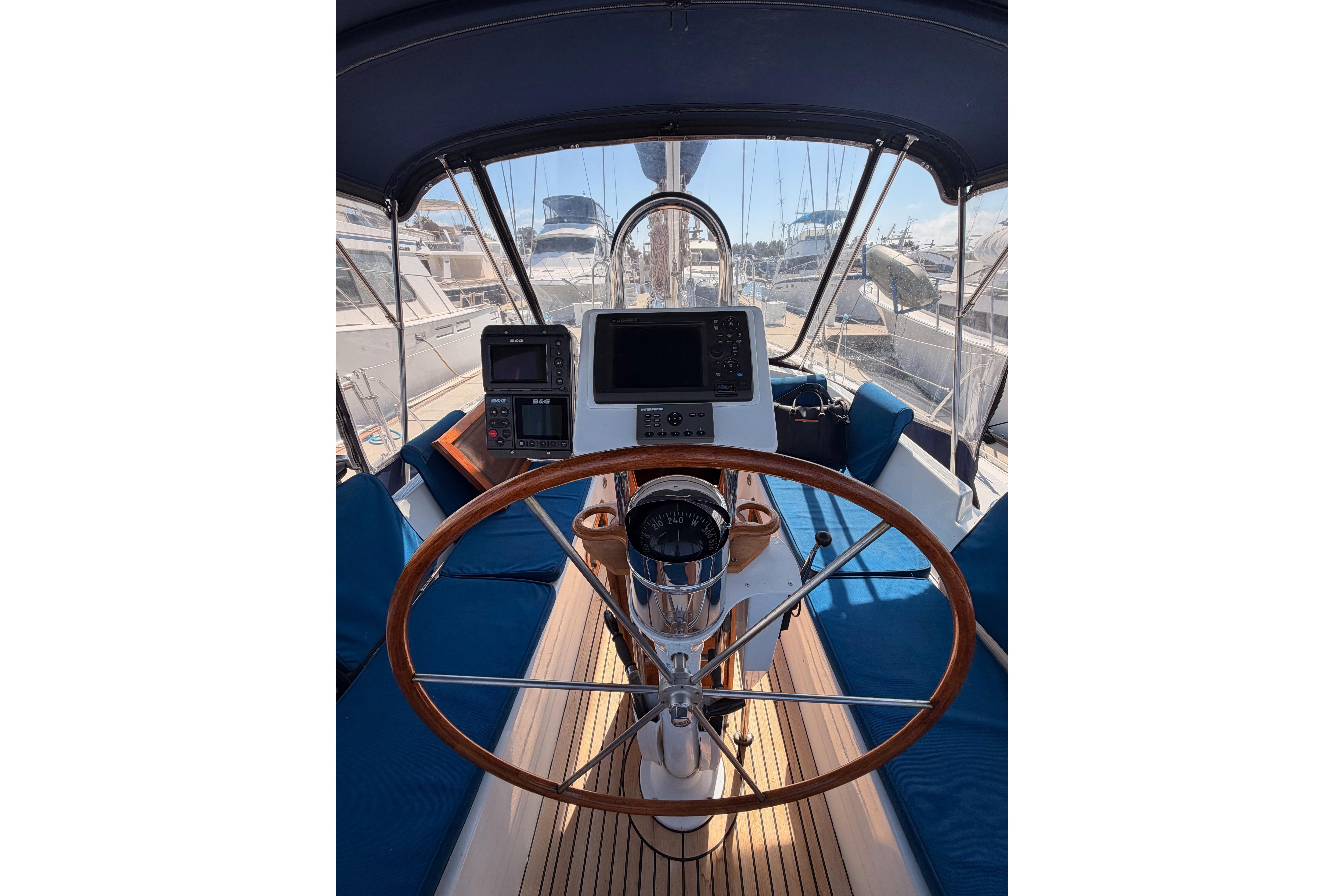 Cockpit of a 1991 Hylas 51 yacht with wooden steering wheel and navigation equipment.