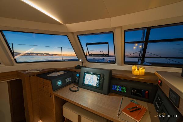 Nautitech 48 Open 2025 yacht interior with navigation equipment and sunset view.
