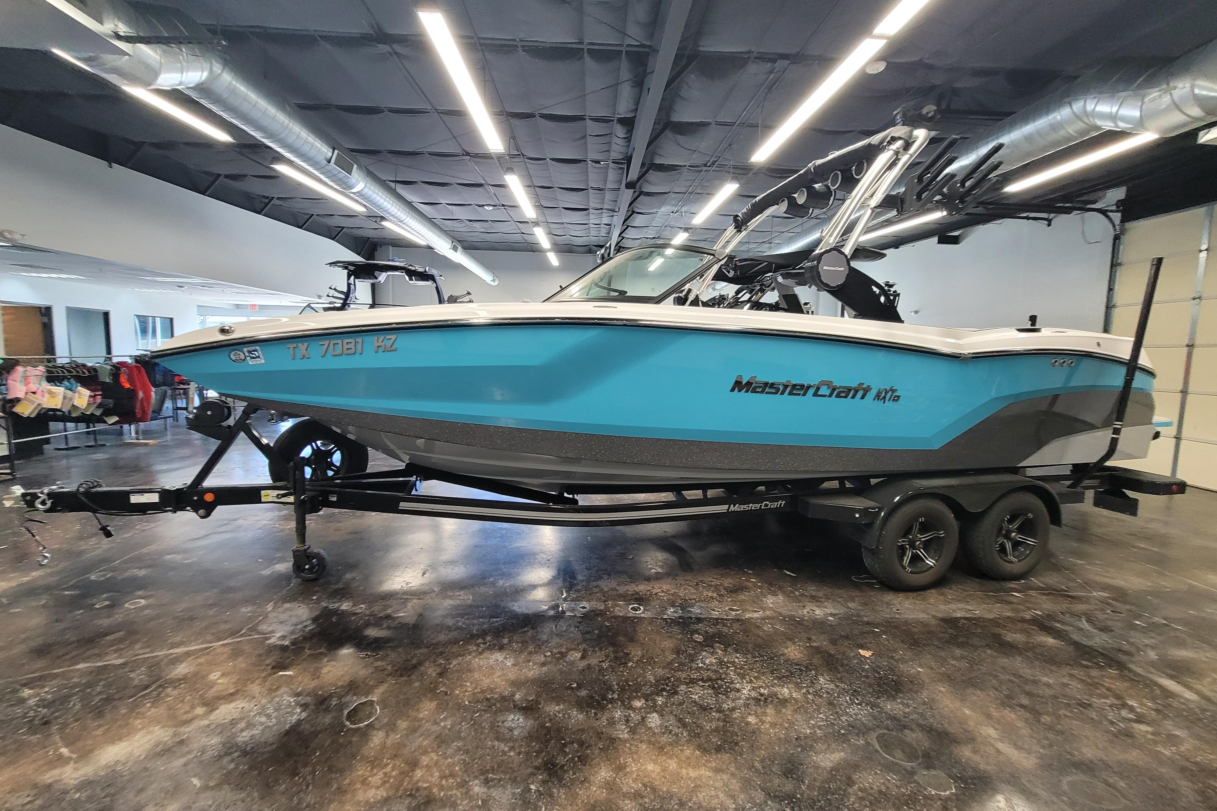2024 MasterCraft NXT24 boat in showroom, blue and white design, on trailer.