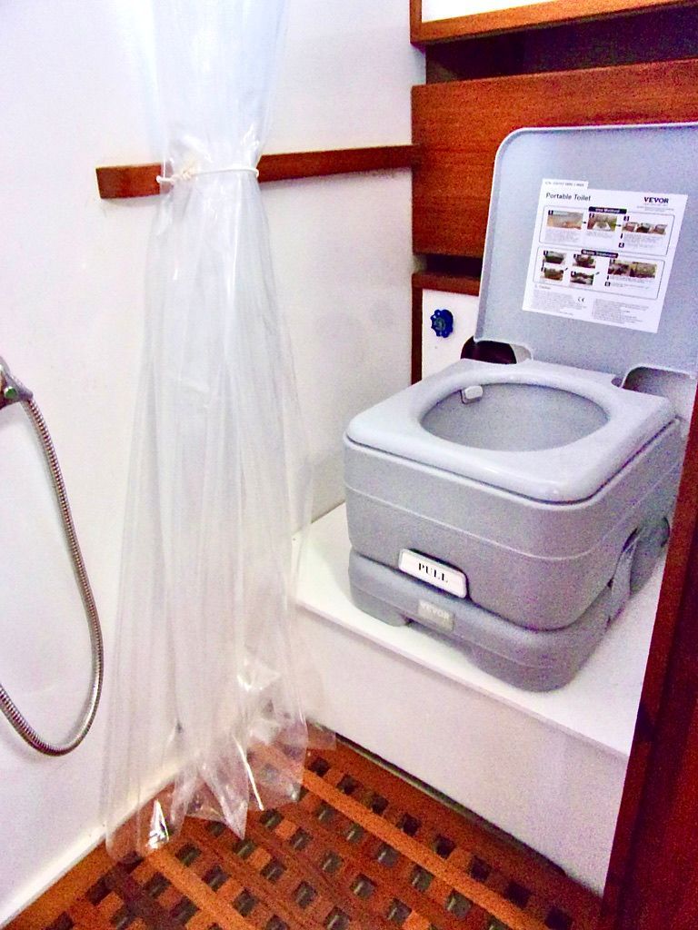 Portable toilet in 1976 CHB Trawler bathroom with shower and wooden flooring.