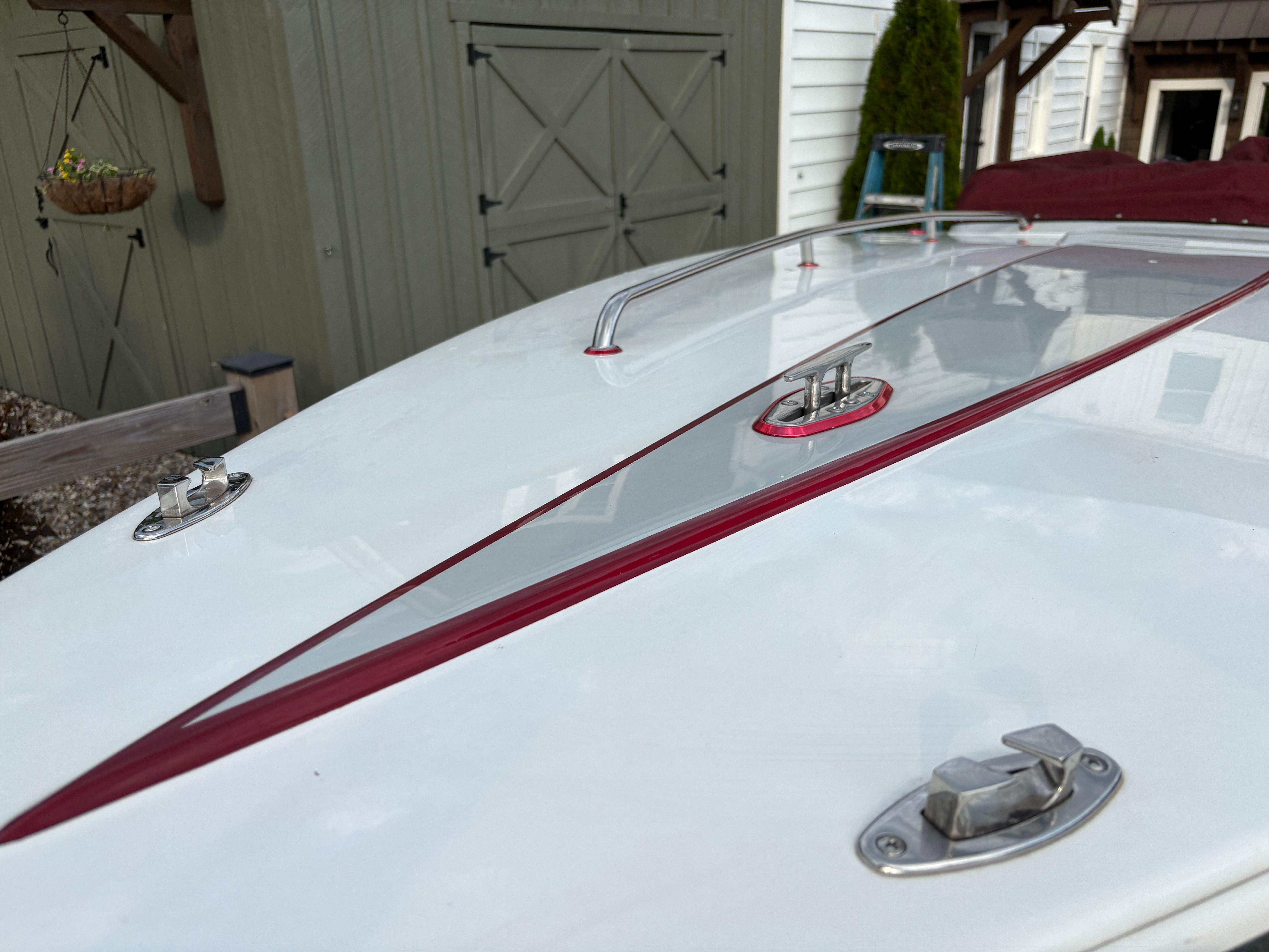 A 1986 Warlock 23 boat with a sleek white deck and red accents.