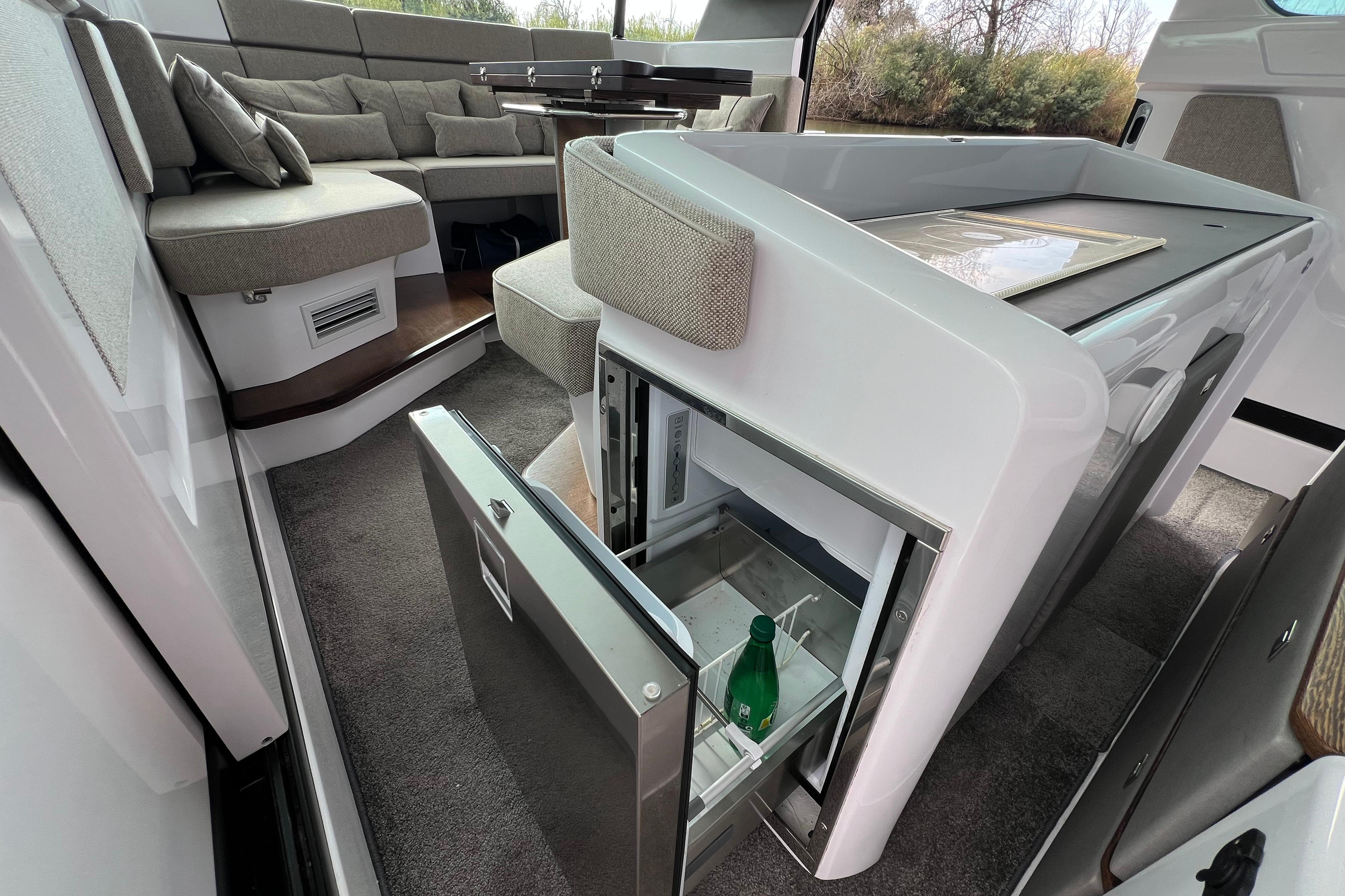 Luxurious interior of 2023 Axopar 45 Cross Cabin with open fridge and seating area.