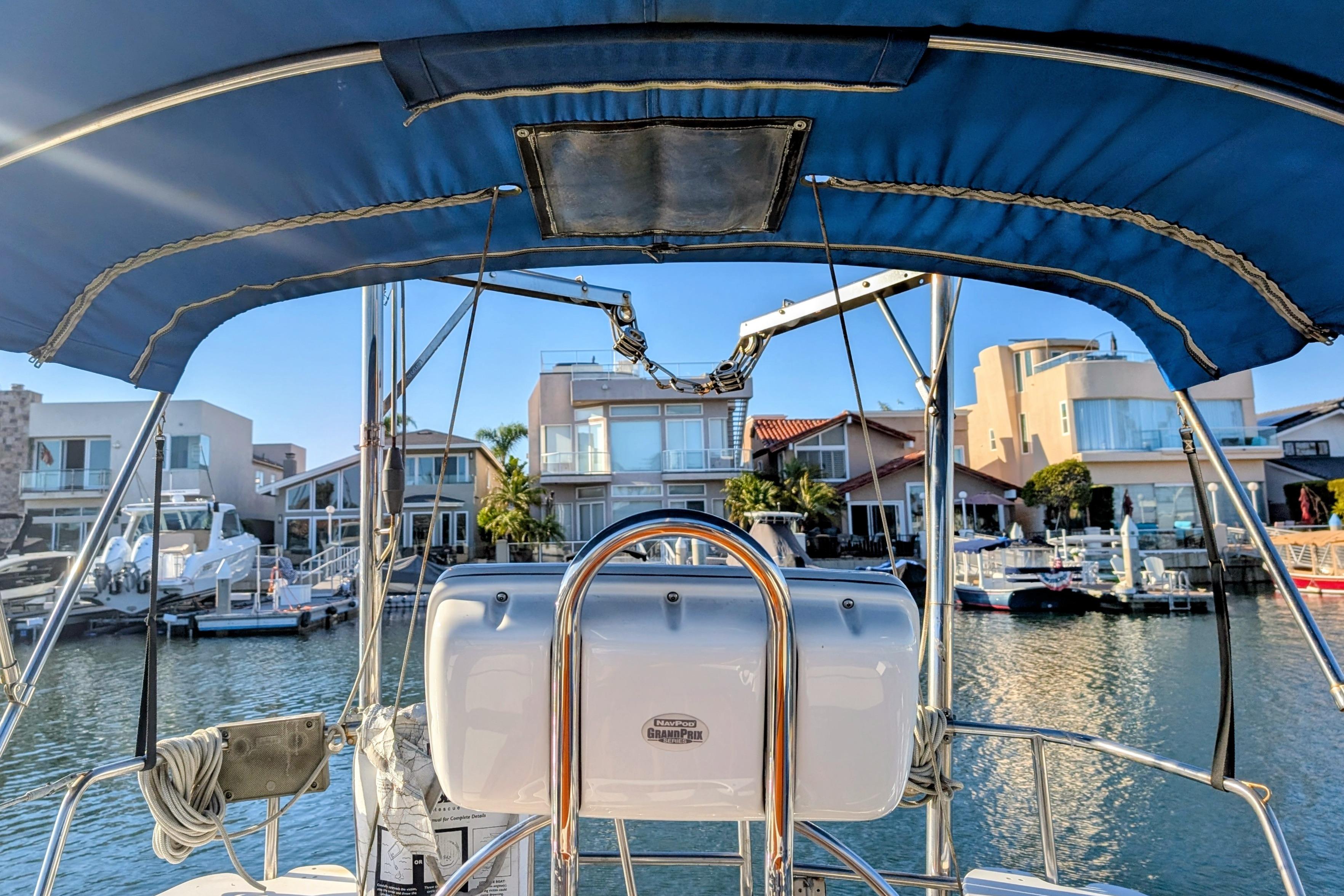 Cockpit view from a 1989 Catalina 34 sailboat in a marina with waterfront homes.