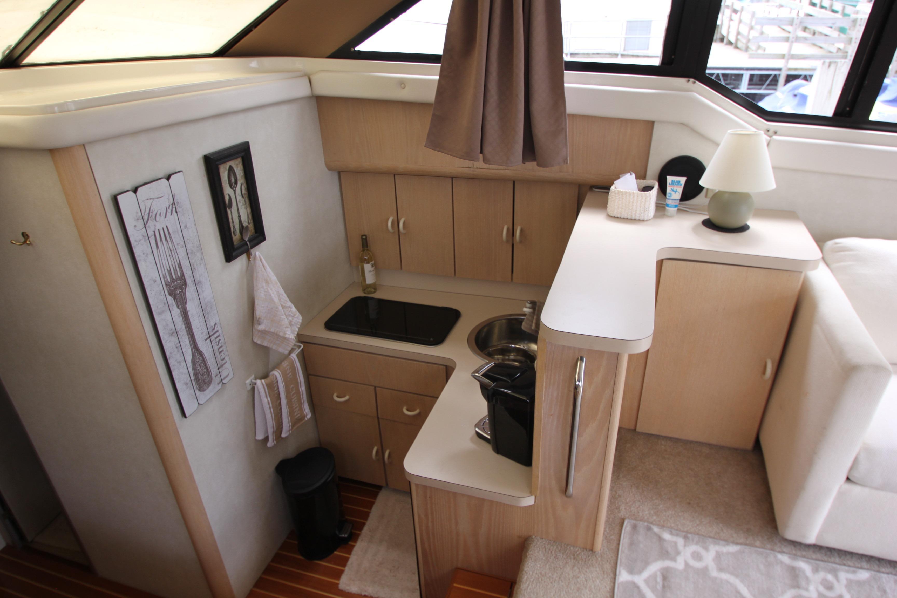 Compact kitchen area in a 1990 Silverton 34 Convertible yacht, featuring modern amenities.