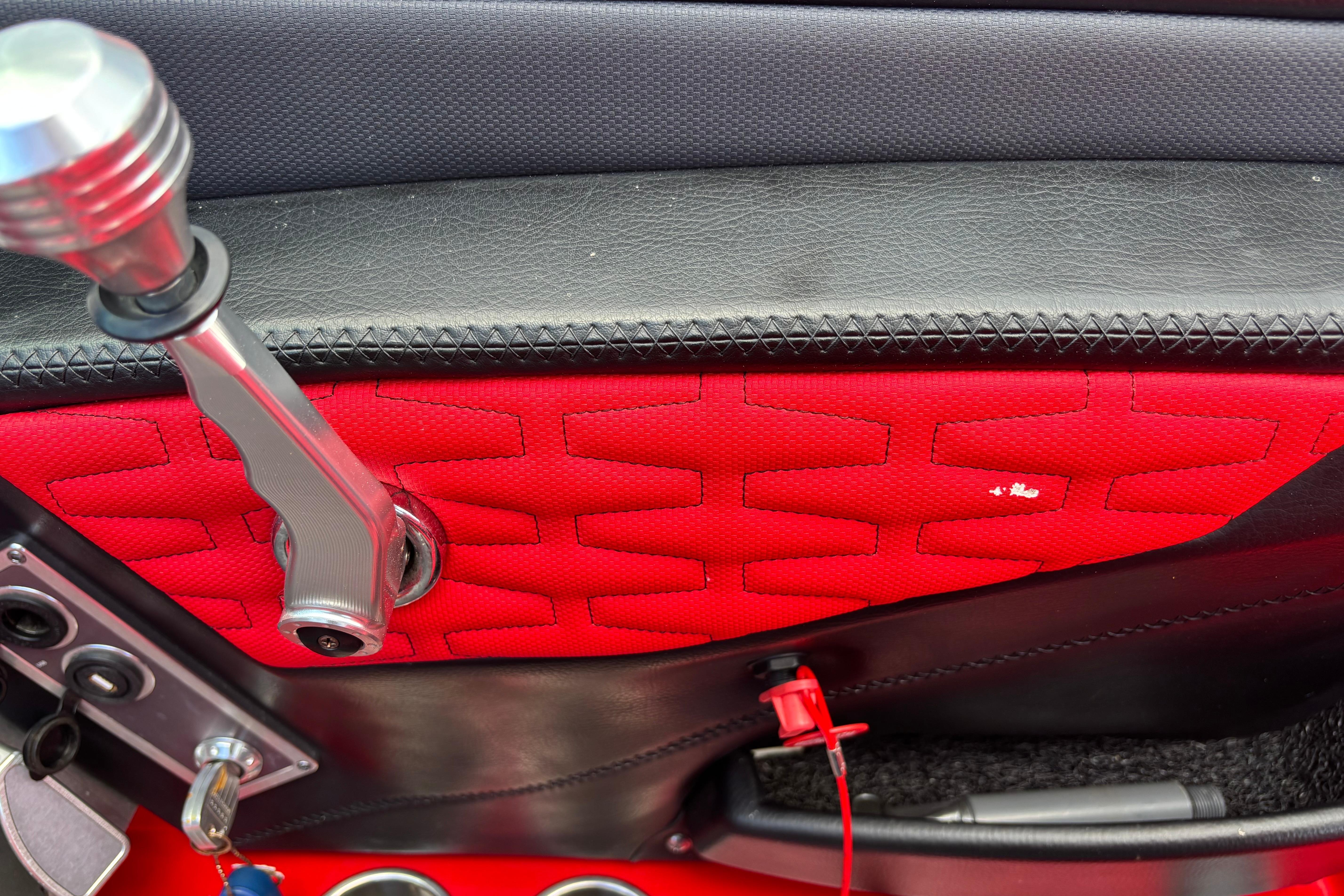 Interior detail of a 2020 MasterCraft X24 boat, featuring red and black upholstery with control lever.