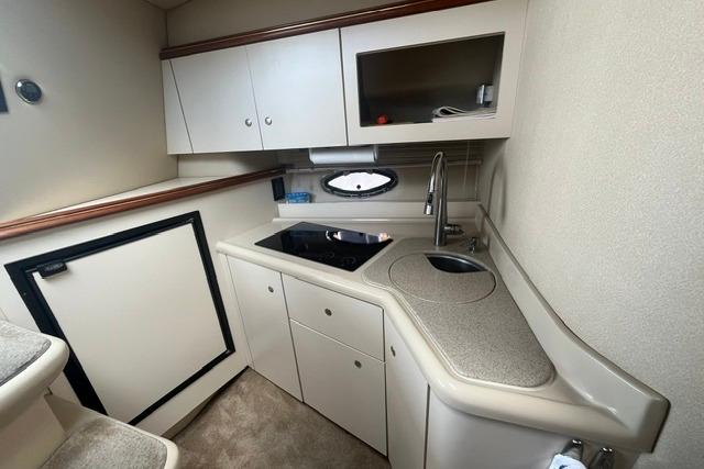 2004 Cruisers Yachts 3372 Express interior kitchen with sink, stove, and storage cabinets.