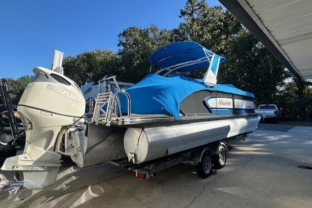 2020 Manitou 25 X-Plode RFW pontoon boat with blue cover and Suzuki outboard motor.