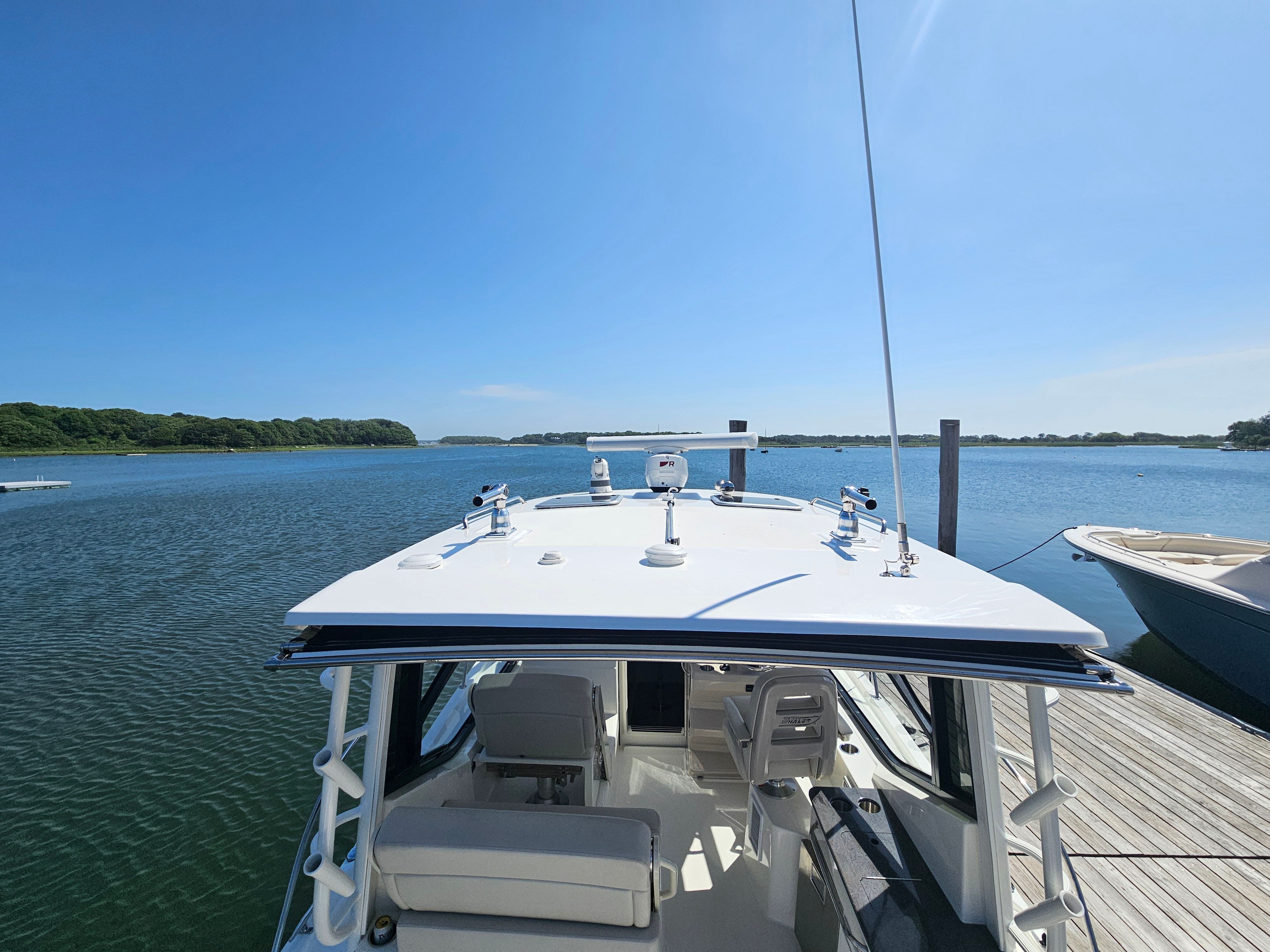 A Boston Whaler 325 Conquest boat docked at a serene pier overlooking the water.