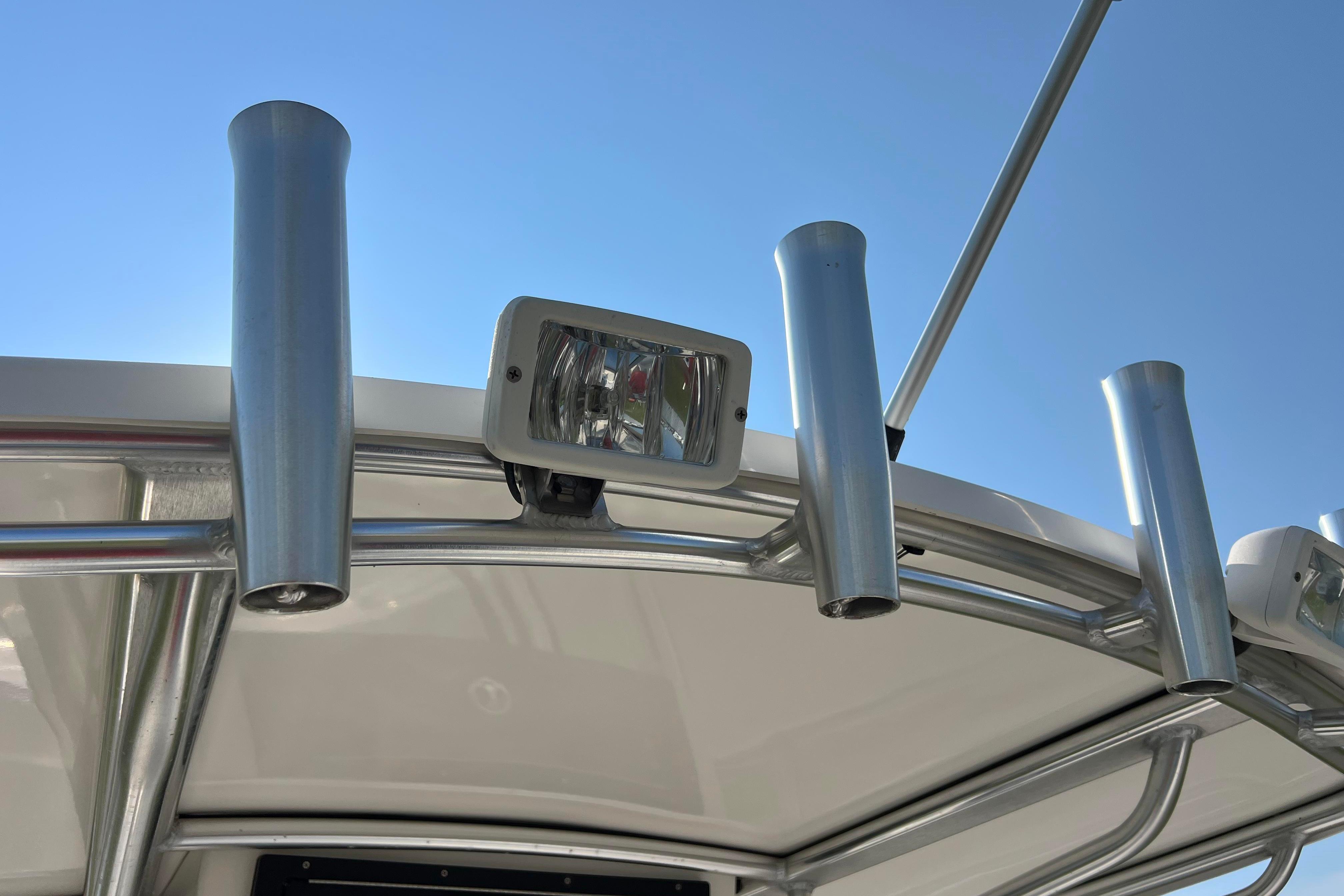 2012 Sea Fox 206 Center Console boat with rod holders and spotlight against clear sky.