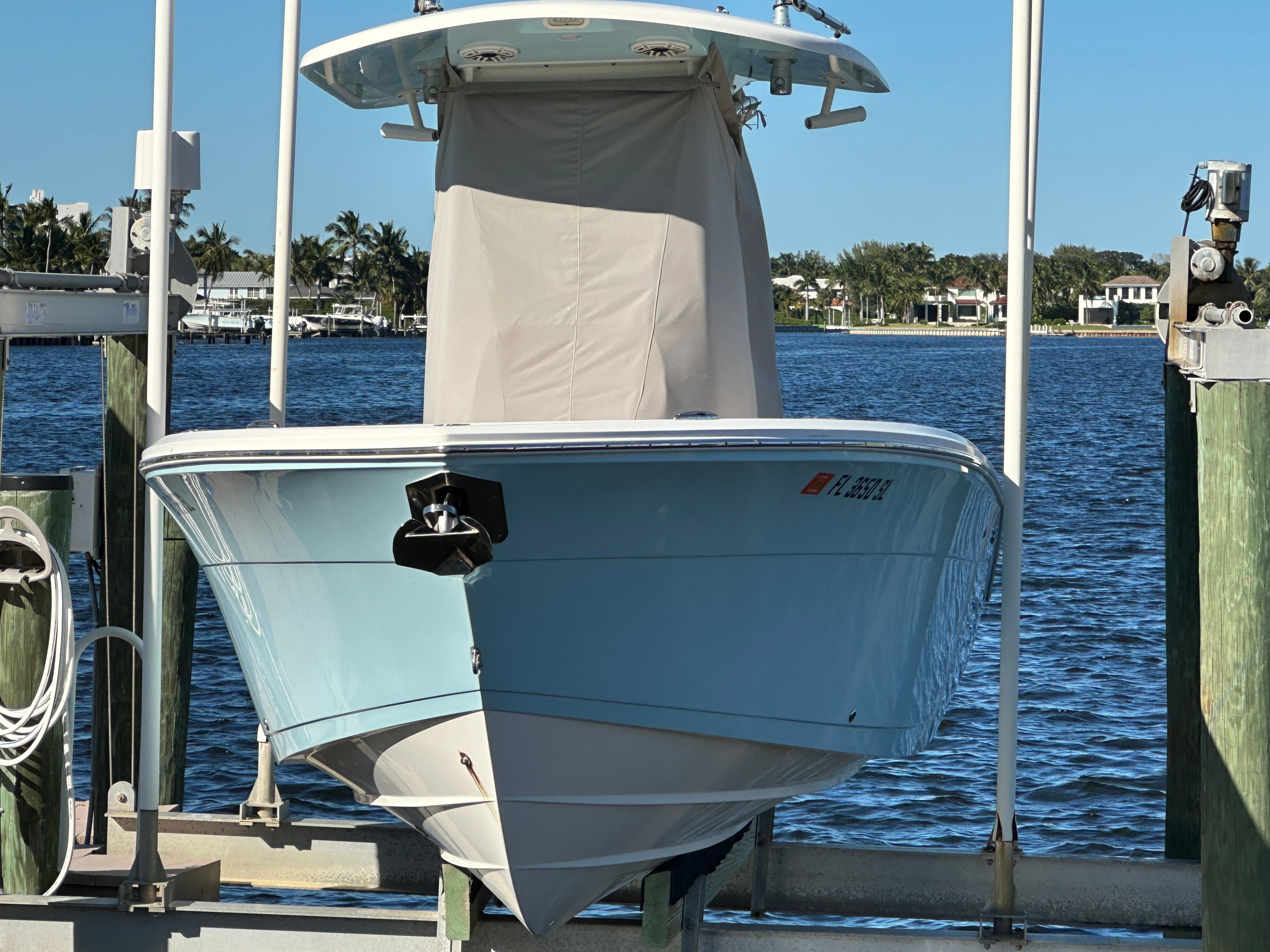 2022 Cobia 240 Center Console on a boat lift by the water.