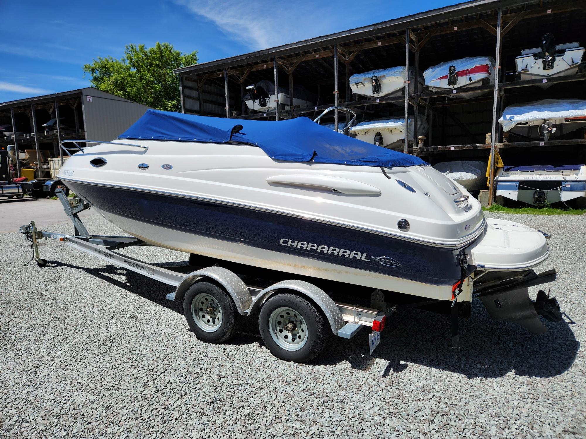 2011 Chaparral 215 SSi boat on trailer with blue cover, parked outdoors.