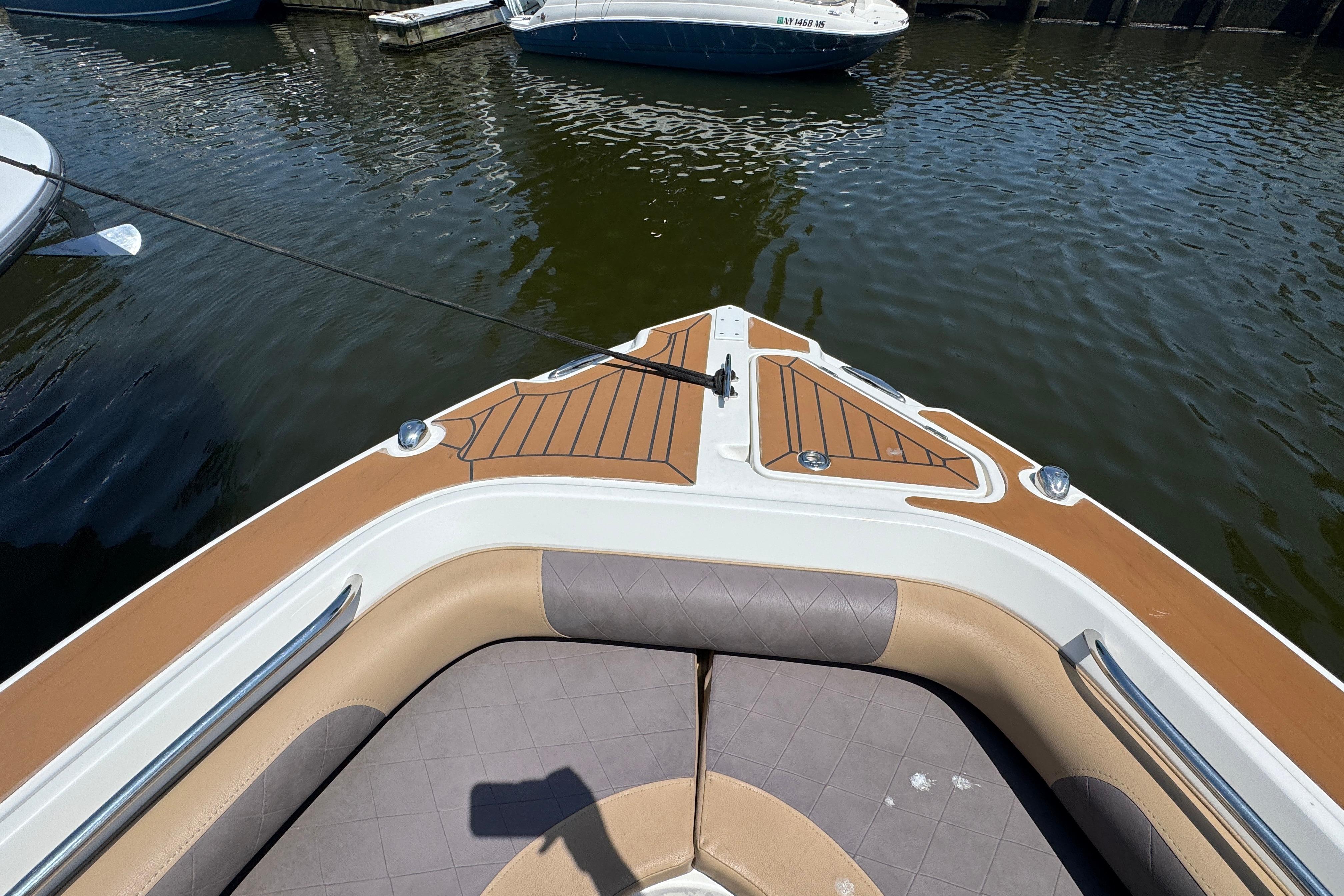 Bow view of a 2014 Century 2301 Center Console boat docked on calm water.