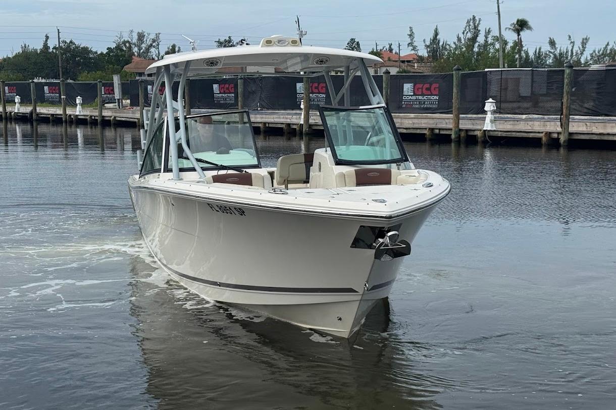 2020 Cobia 280 Dual Console boat on calm water near a dock.