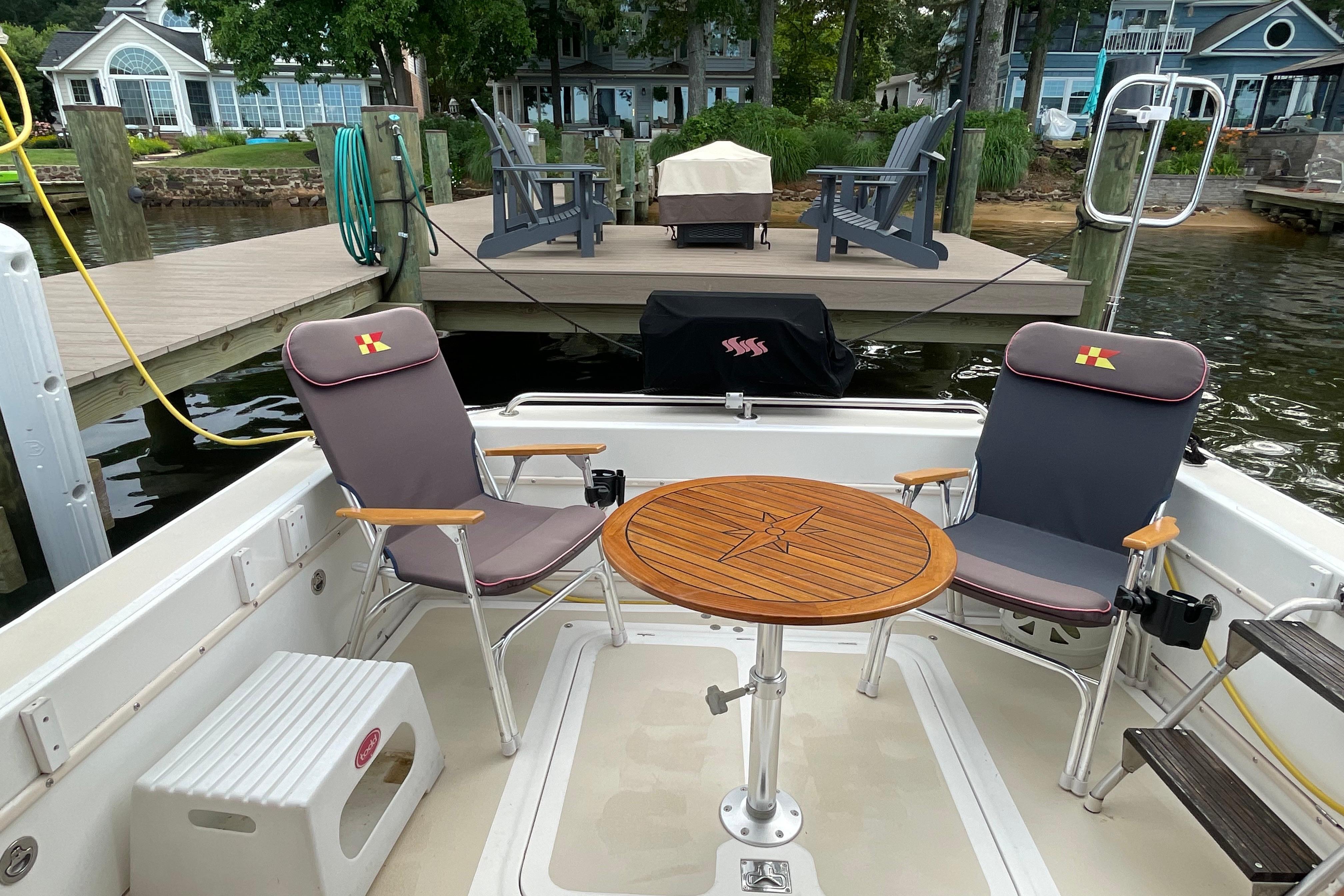 Fox Island Thirty Sedan Cruiser 2005 with chairs and table, docked by a lakeside deck.