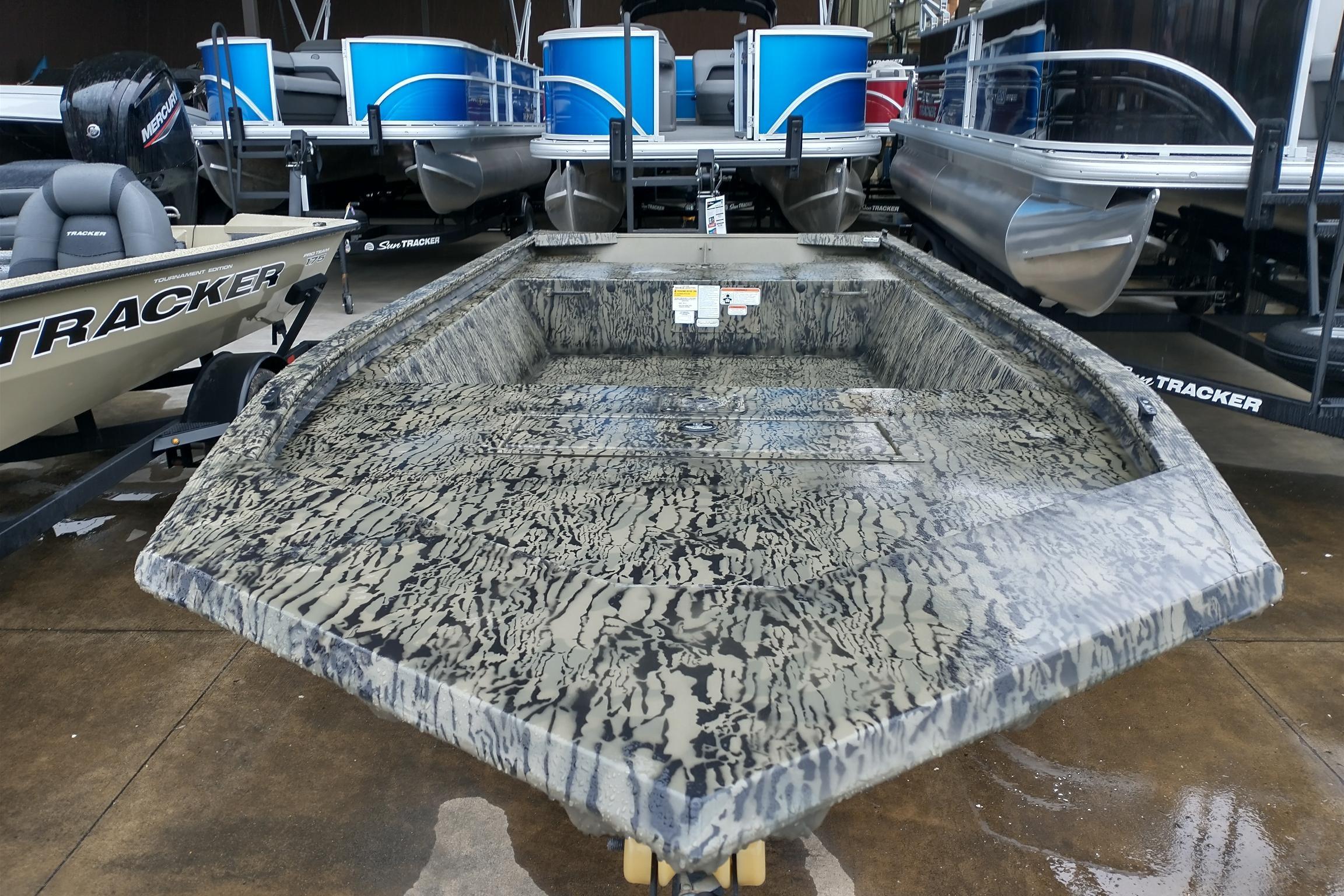 2026 Tracker Grizzly 1648 Utility boat with camouflage design, displayed in a showroom.